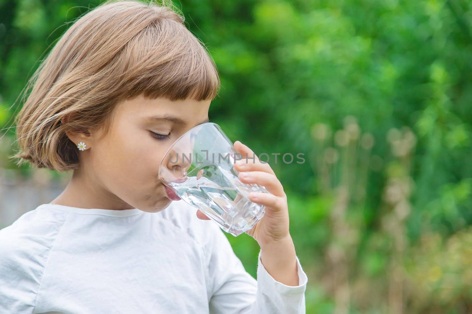 child drinks water from a glass. Selective focus.