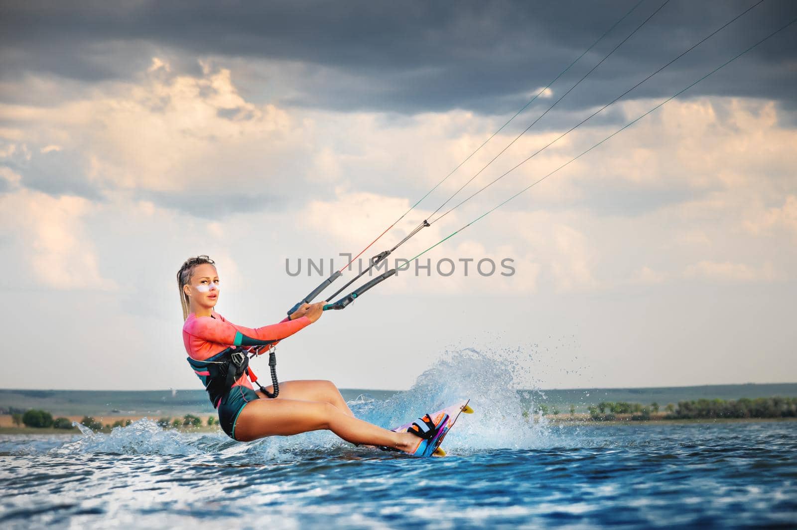 A young woman kitesurfer rides the waves doing a trick. Marine sports. kitesurfing.