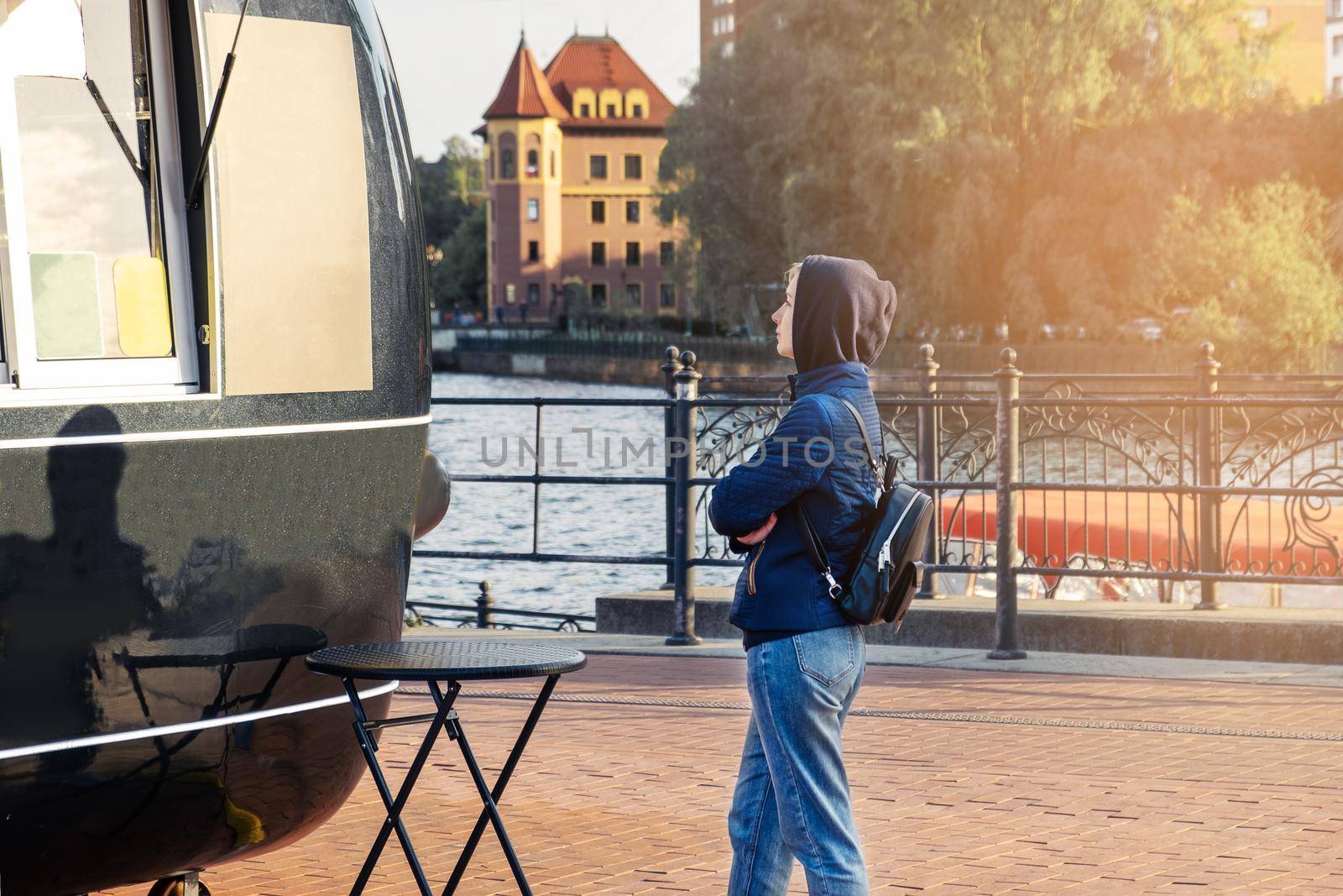 Young woman stands near food truck and reads menu by OlgaGubskaya