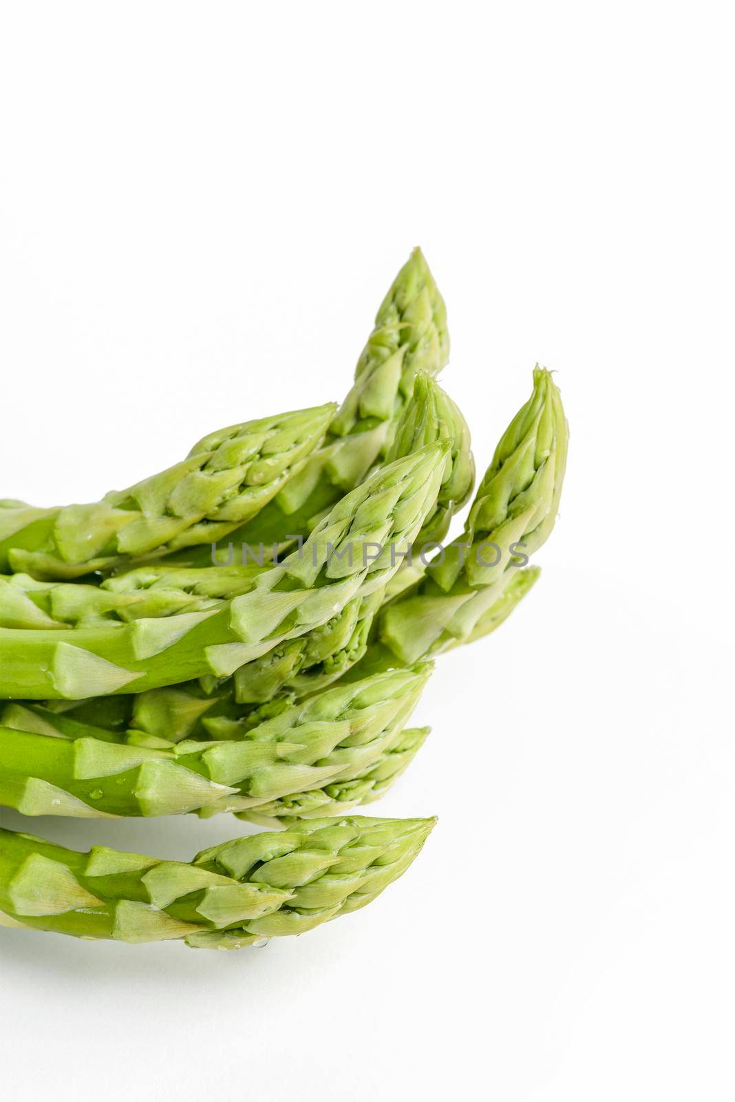 Bunch of fresh green asparagus isolated on white background. Freshly picked asparagus with water drops isolated on white background. by SERSOL