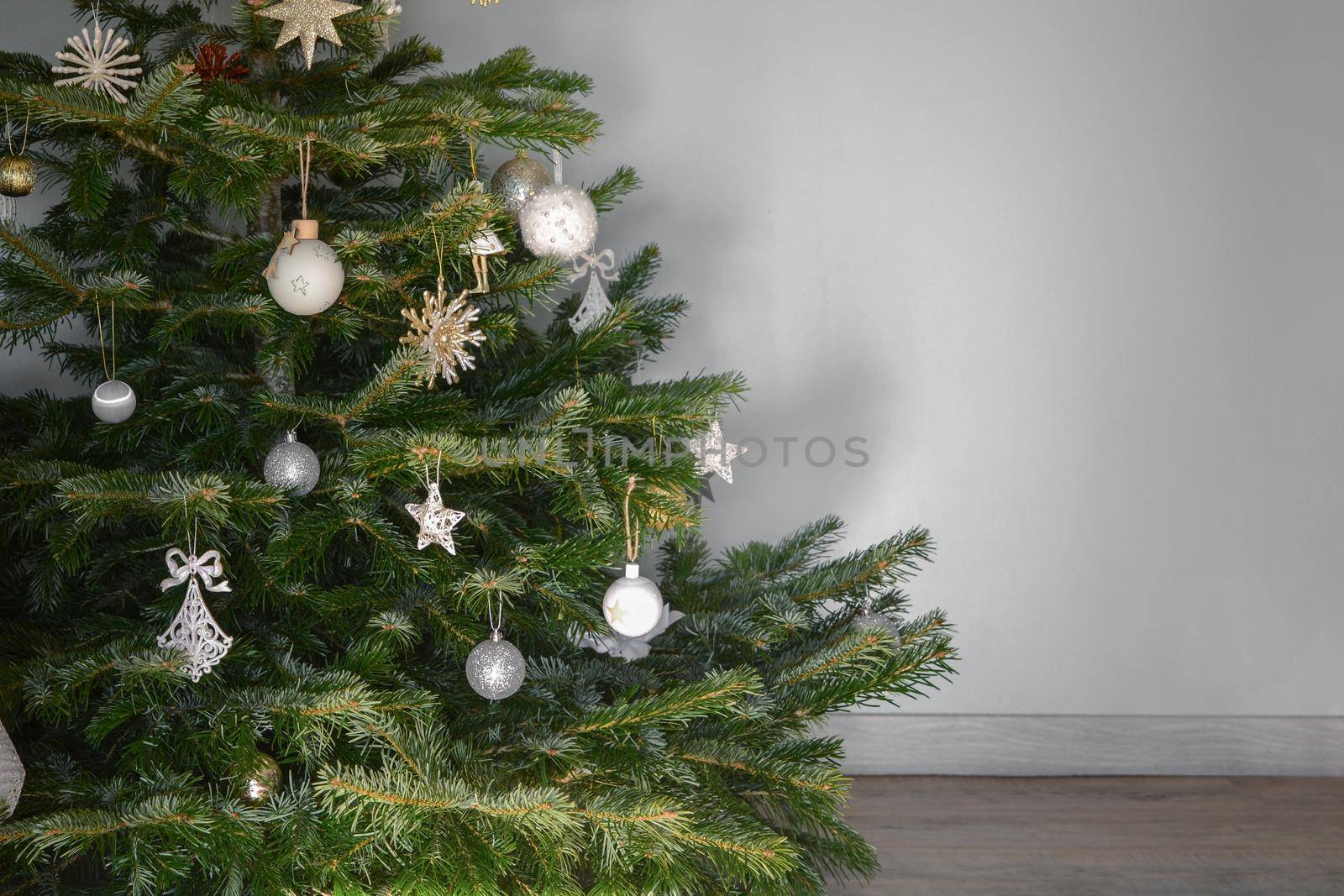 Christmas tree decorated with toys against a gray wall