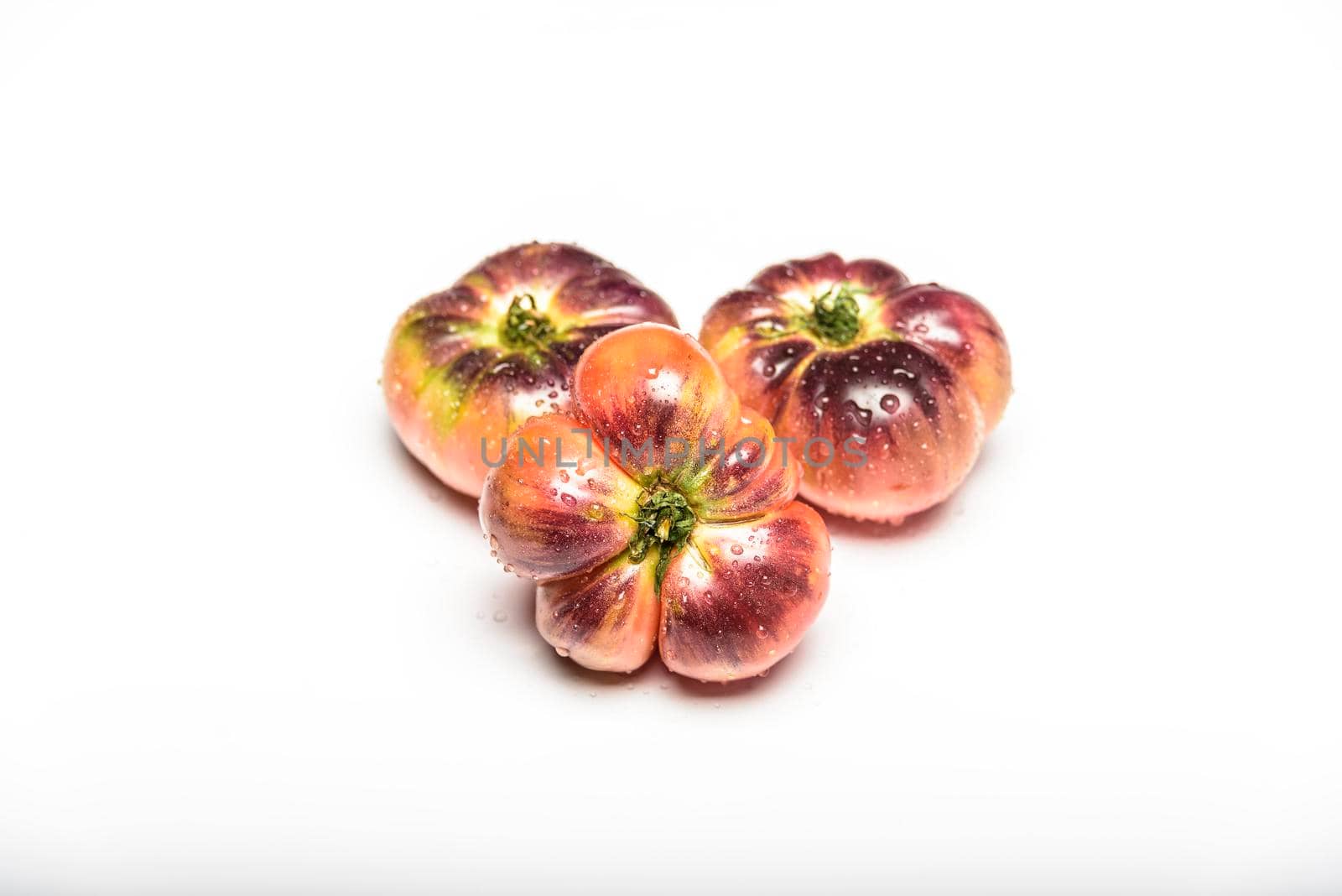 Several tomatoes of the tiger variety on a white background