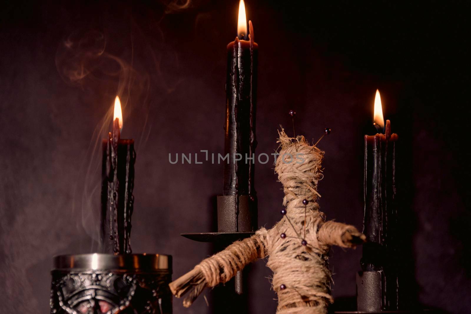 Scary voodoo doll with black candles. Mystic background with ritual esoteric objects, occult and halloween concept