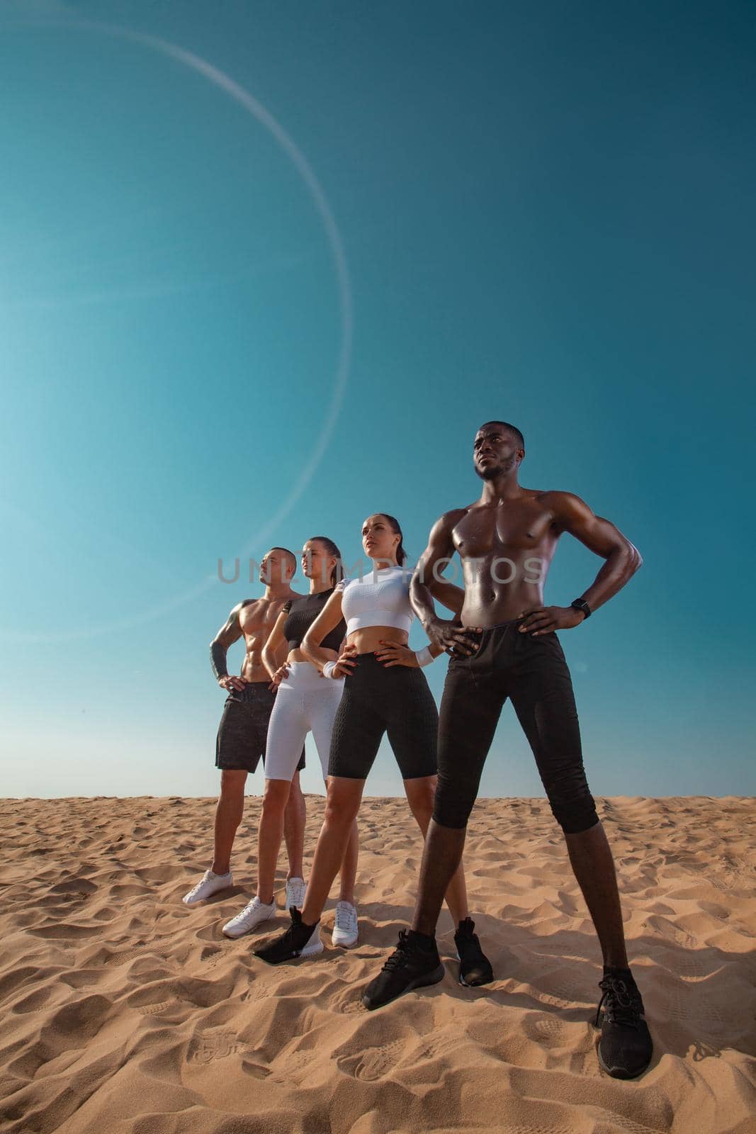 Fitness and sport concept. Group of four young sportsmens women and men, fit athletes are standing on the sky background before run. Healthy lifestyle. Friends in black and white sportswear. by MikeOrlov