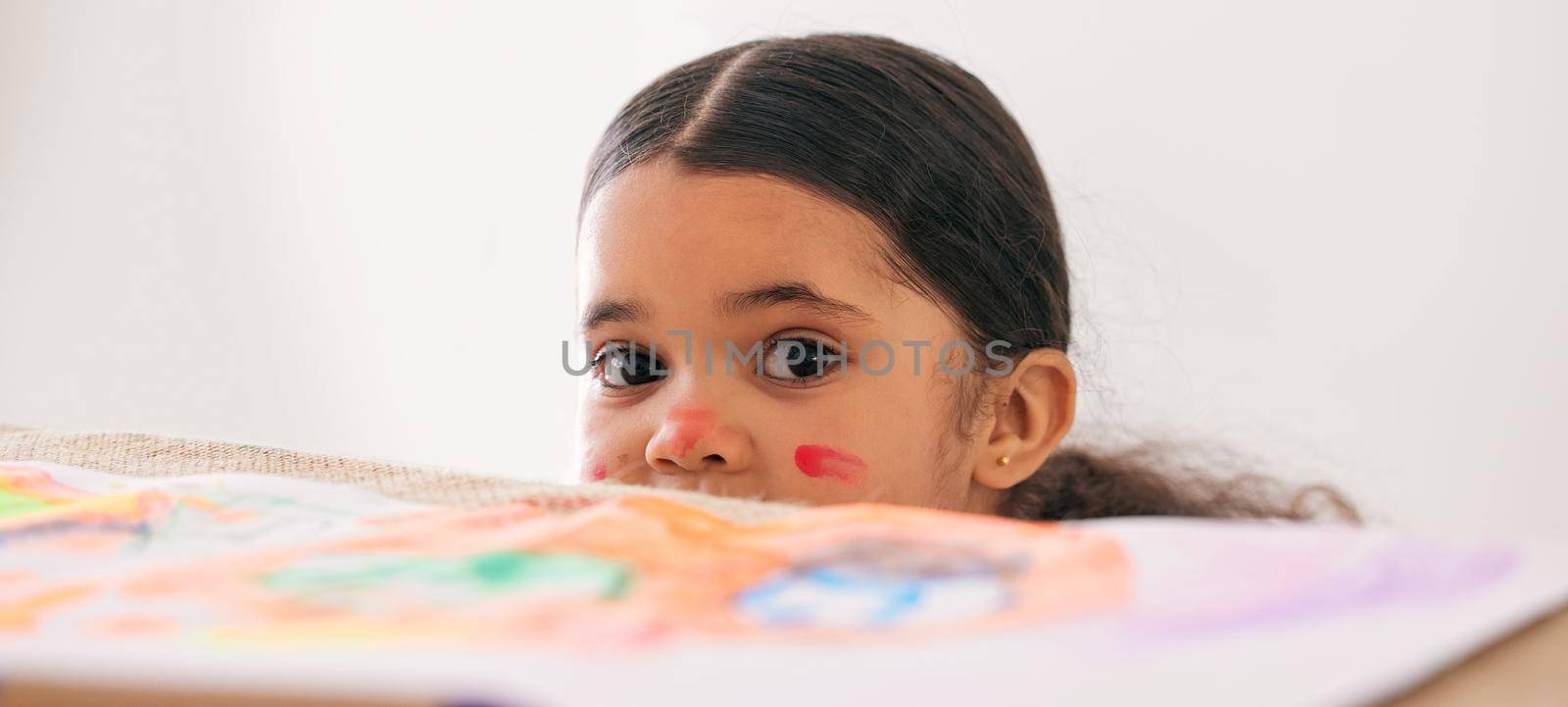 Shot of an adorable little girl peeking over a table while busy doing art.