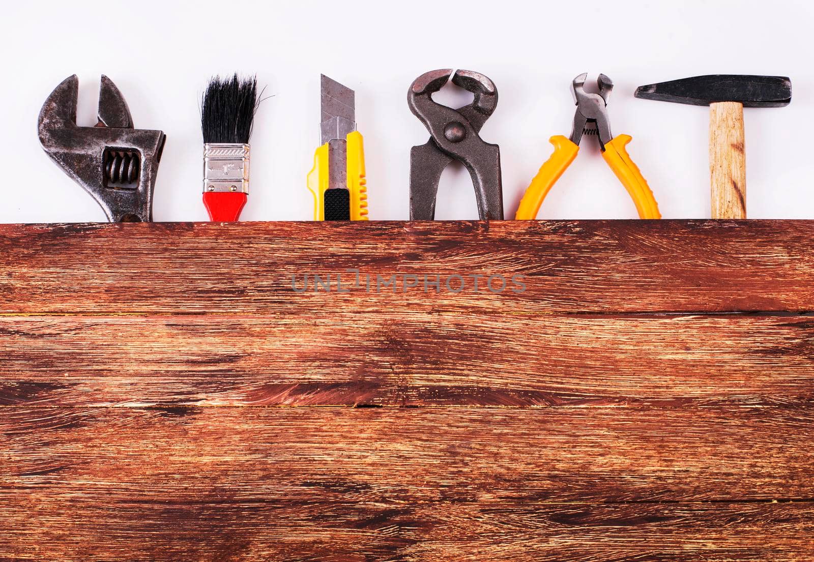 This is an overhead photo of construction tools and brush with copy space on a wood background. There is a lot of space