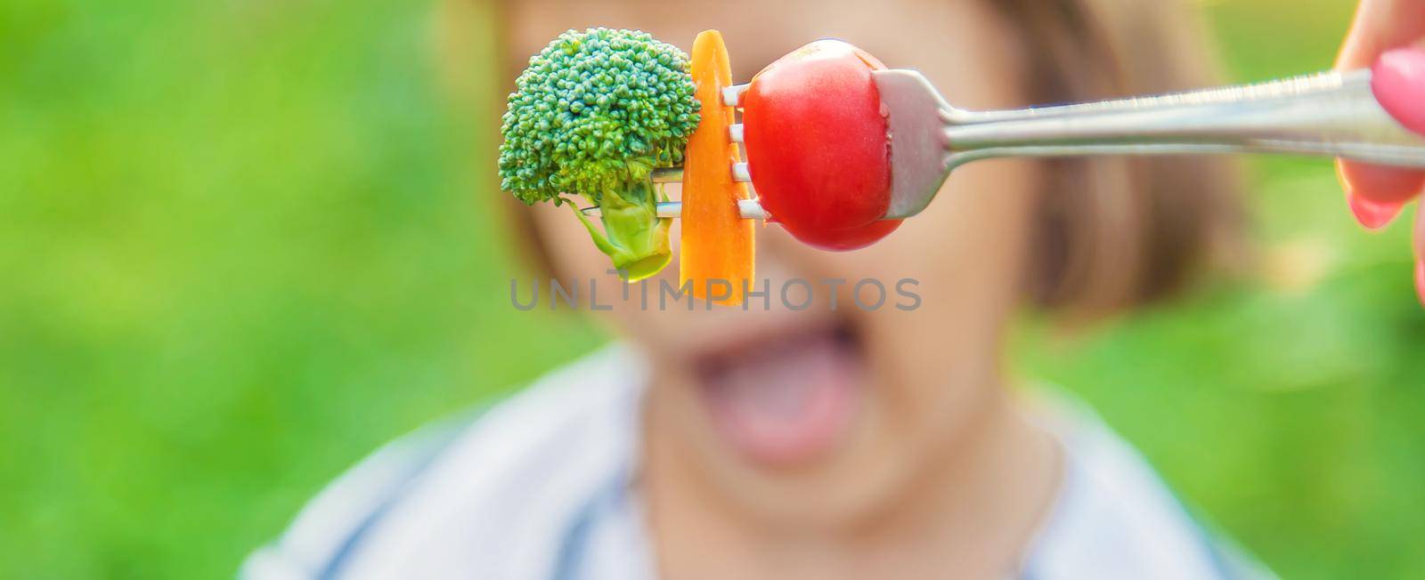 child eats vegetables broccoli and carrots. Selective focus. nature.