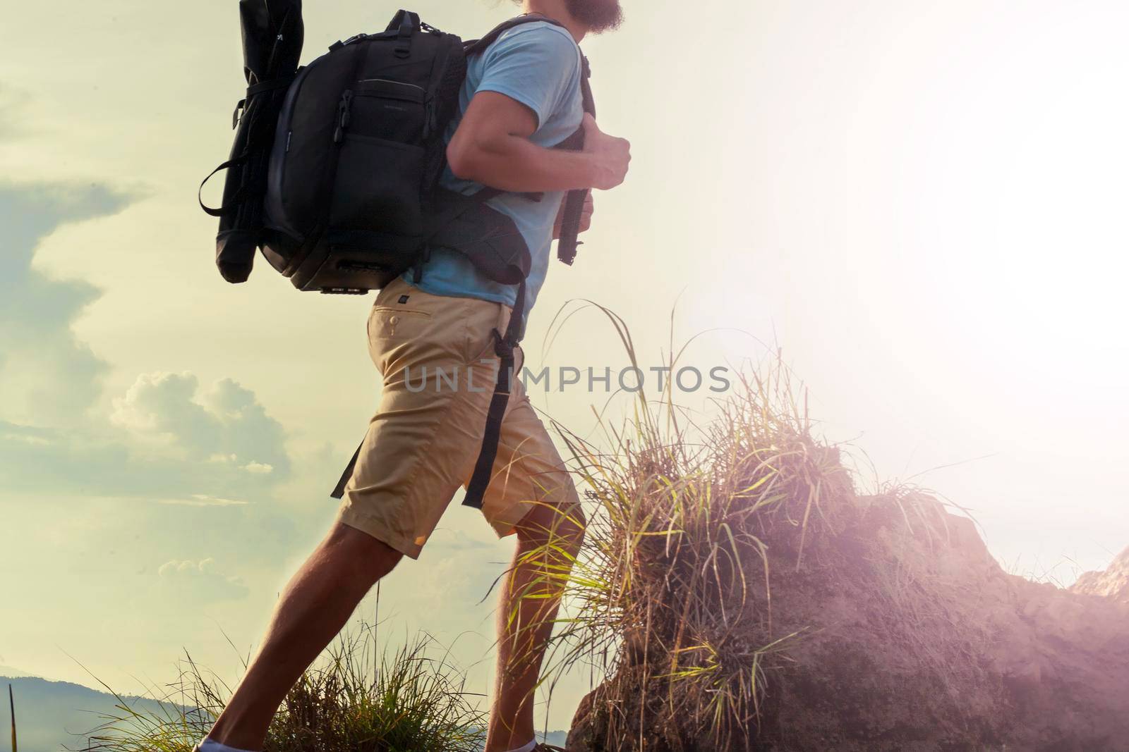 Hiker walking along a mountain path. Sunrise on top of mountain - Stock image