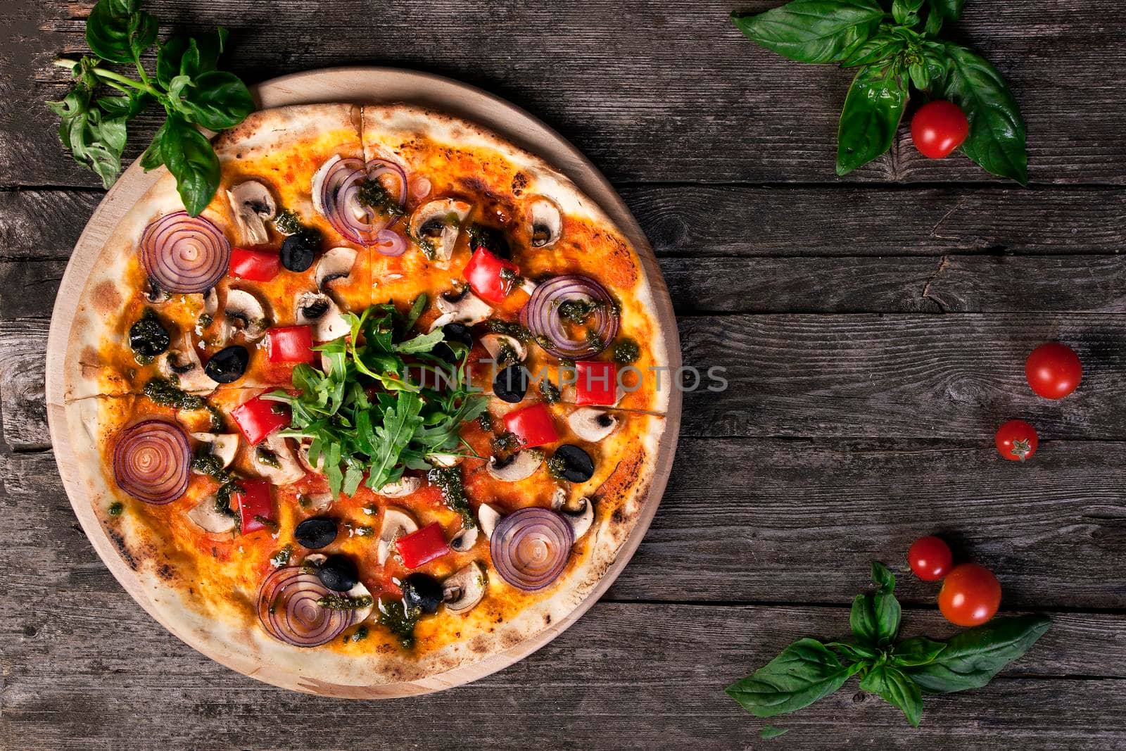 Delicious fresh pizza with onions , black olives , peppers , mushrooms and arugula on the wooden background. Top view.