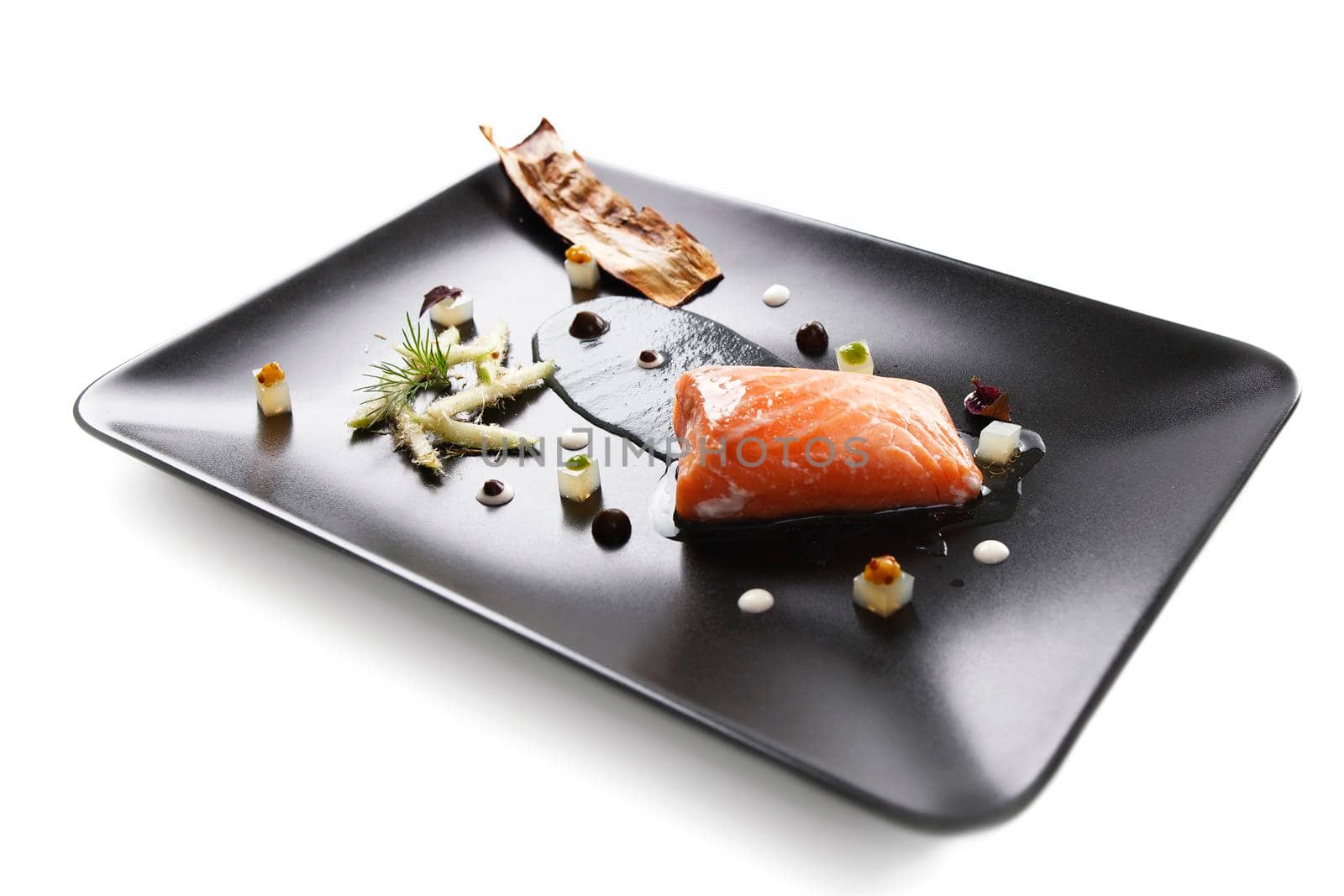 Molecular modern cuisine red fish in a dish with beautiful garnish close up. Isolated