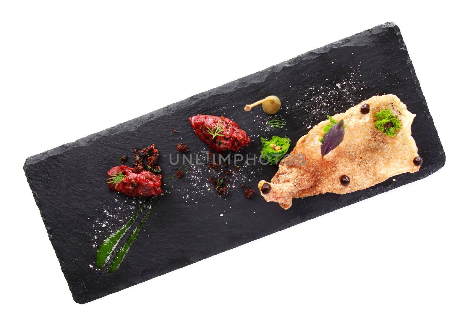 Molecular modern cuisine. Chips Pigskin with tartare or carpaccio of beef. Stock image. Isolated on white.