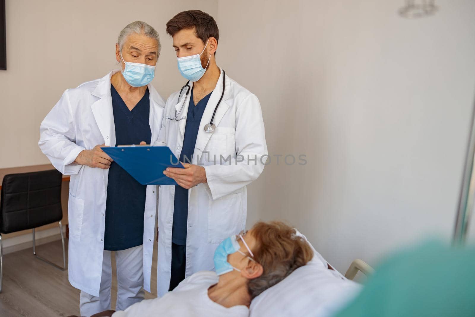 Professional doctors discuss over patient's diagnosis standing in hospital ward. High quality photo