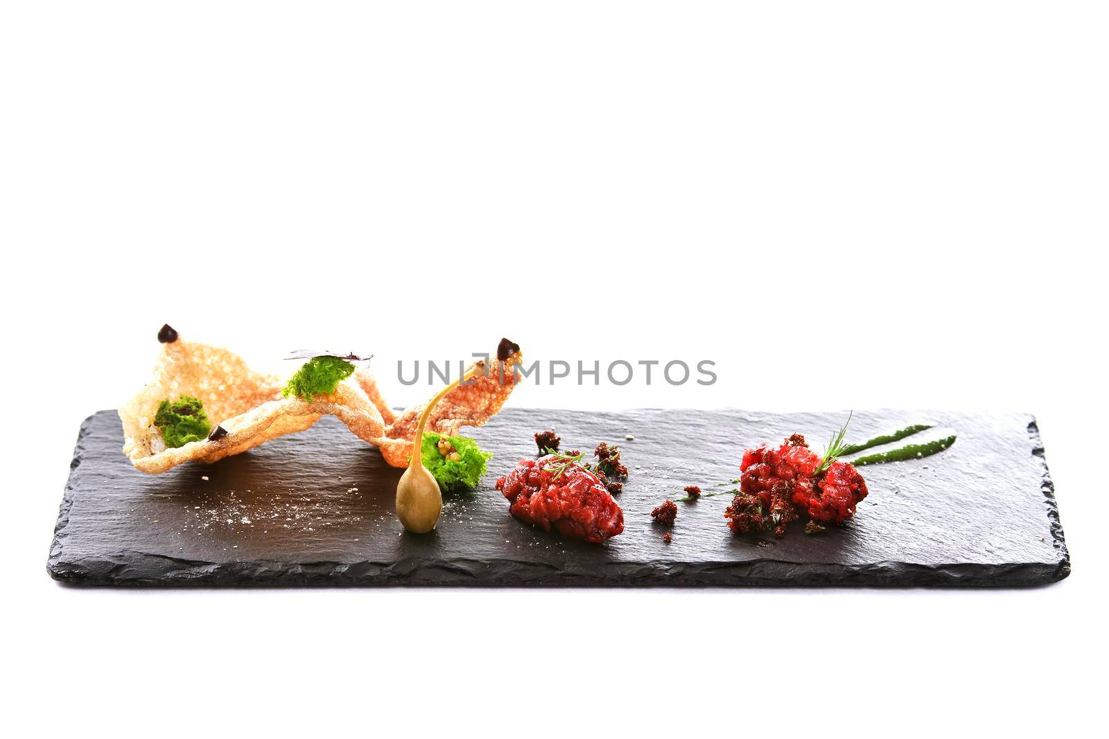 Molecular modern cuisine. Chips Pigskin with tartare or carpaccio of beef. Stock image. Isolated on white.