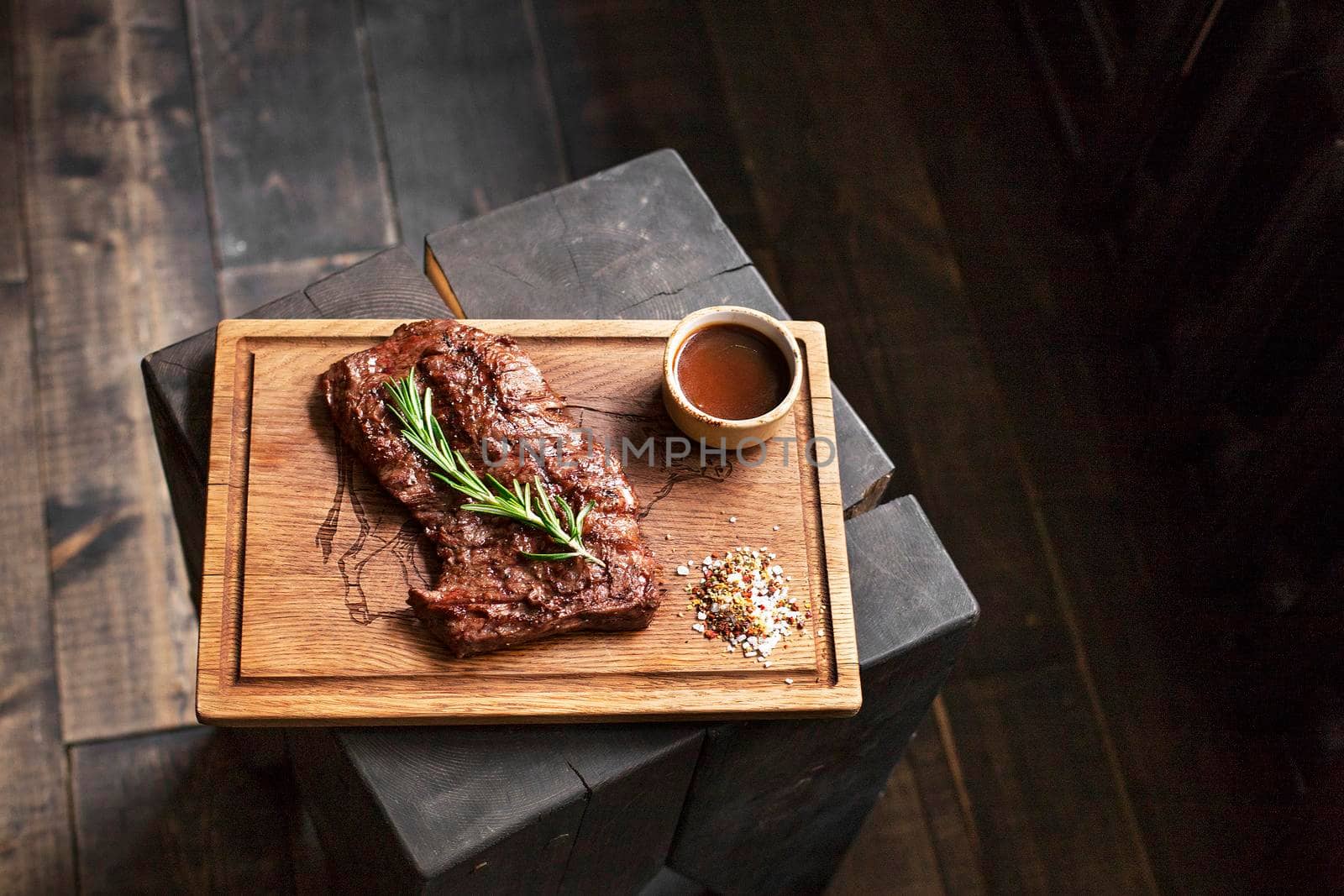 Beef steak. Piece of Grilled BBQ beef marinated in spices and herbs on a rustic wooden board over rough wooden desk with a copy space. Top view