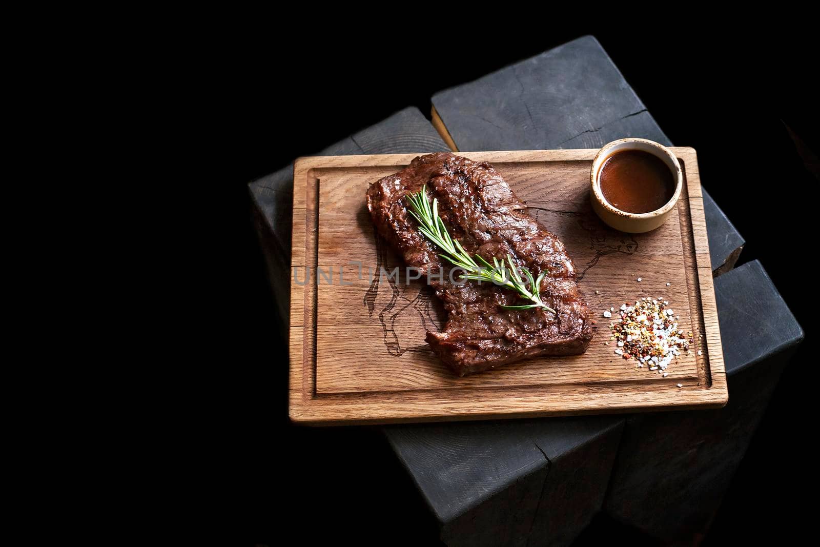 Beef steak. Piece of Grilled BBQ beef marinated in spices and herbs on a rustic wooden board over rough wooden desk with a copy space. Top view. Stock Image