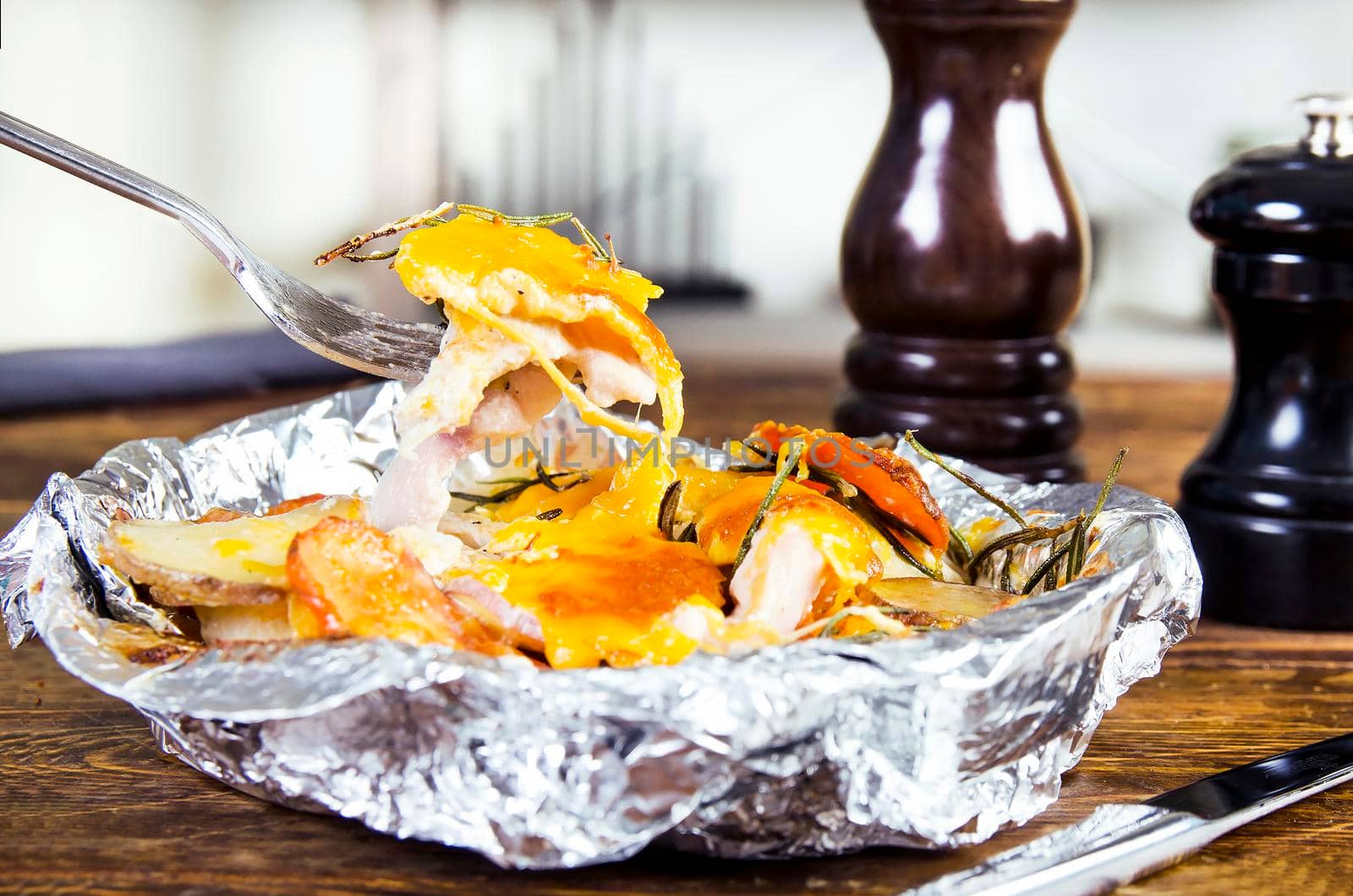 Meat with vegetables in foil. Wooden background.
