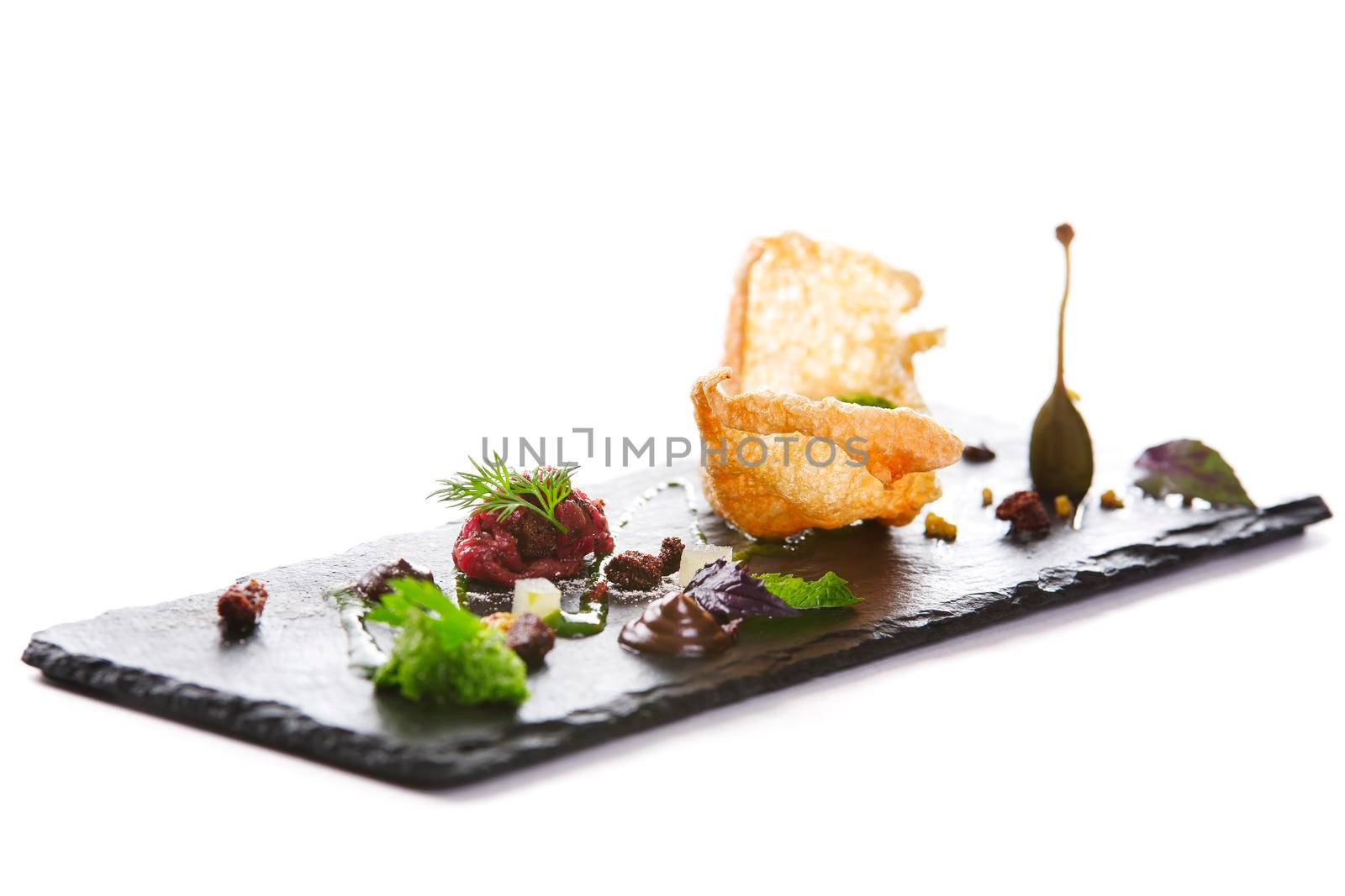 Molecular modern cuisine. Chips Pigskin with tartare or carpaccio of beef. Stock image. Isolated on white.