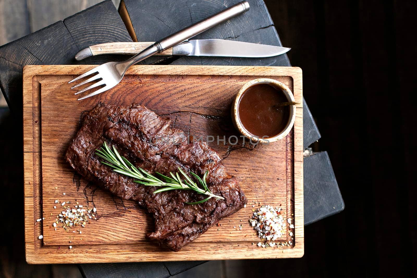 Beef steak. Piece of Grilled BBQ beef marinated in spices and herbs on a rustic wooden board over rough wooden desk with a copy space. Top view