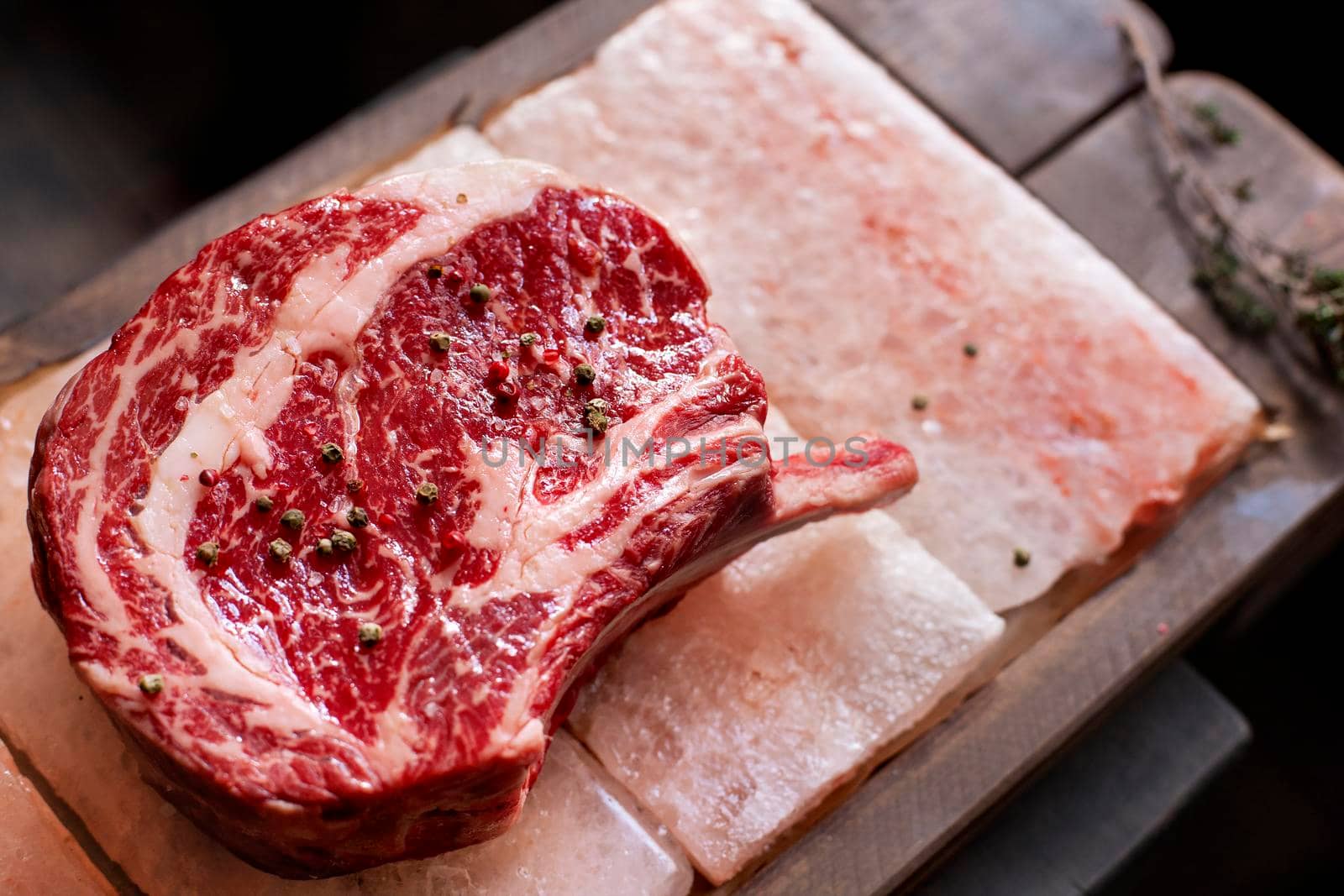 Bone In Rib Eye row Steak on pieces of salt on a wooden board. Stock image