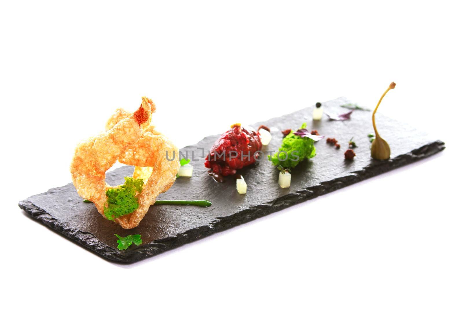 Molecular modern cuisine. Chips Pigskin with tartare or carpaccio of beef. Stock image. Isolated on white.