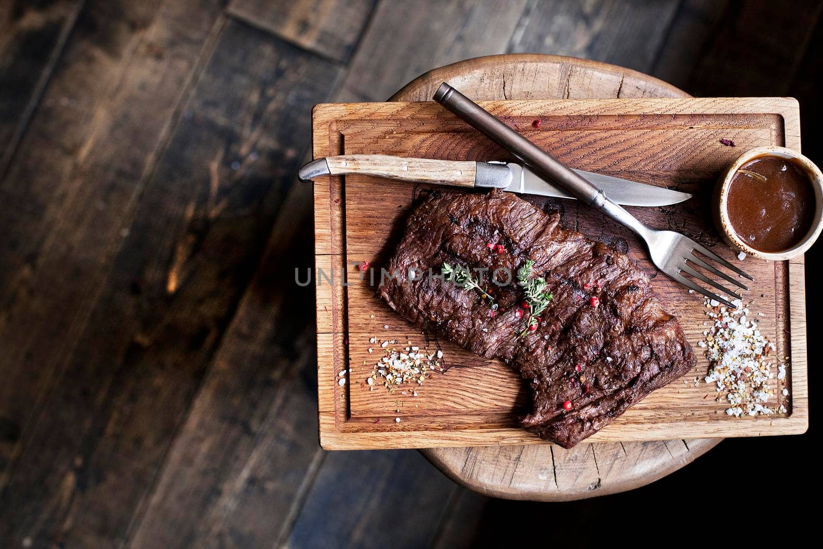 Beef steak. Piece of Grilled BBQ beef marinated in spices and herbs on a rustic wooden board over rough wooden desk with a copy space. Top view. Stock Image