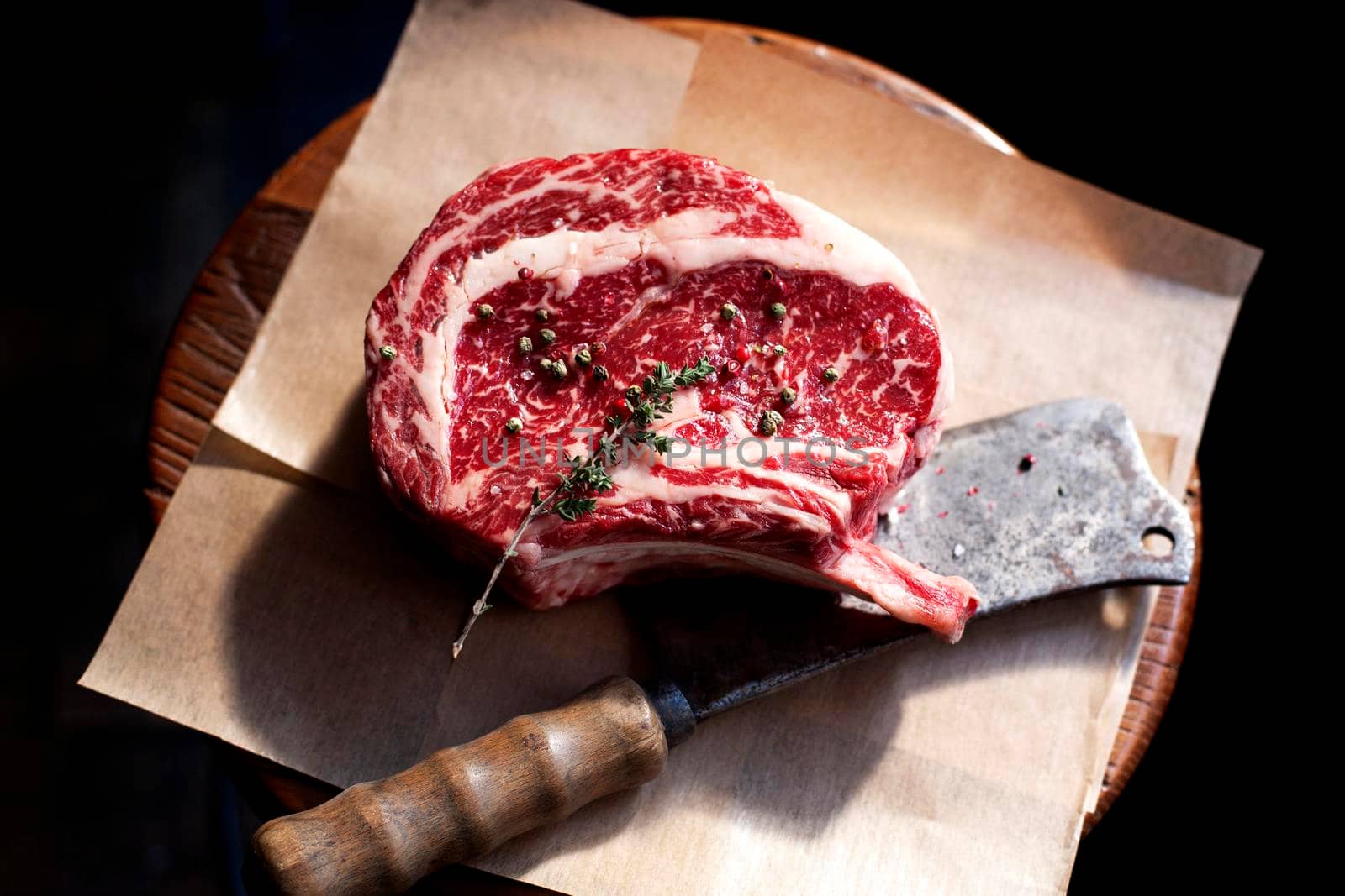 Bone In Rib Eye row Steak and knife for cutting meat on a wooden board. Stock image