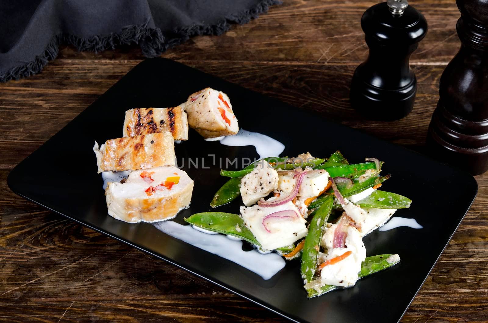 Stuffed turkey breast on the black plate snd wooden background. Chicken roulade - Stock image