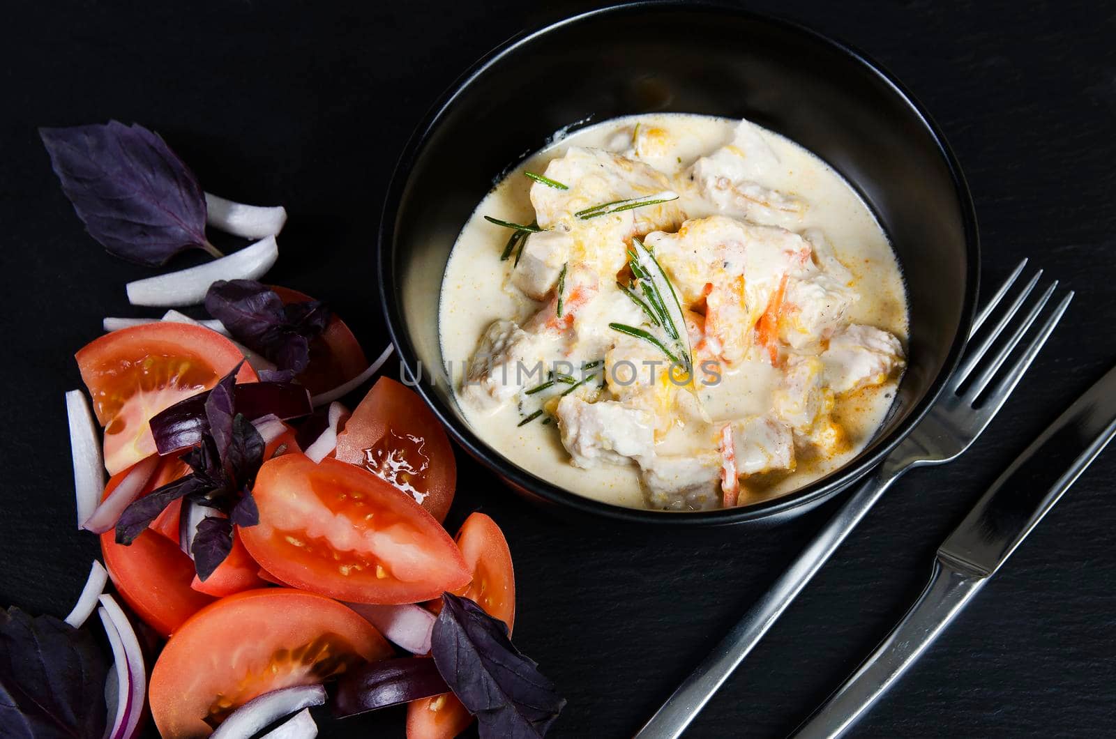 Braise fillet slices of turkey, chicken in a creamy sauce with vegetables. Black background.