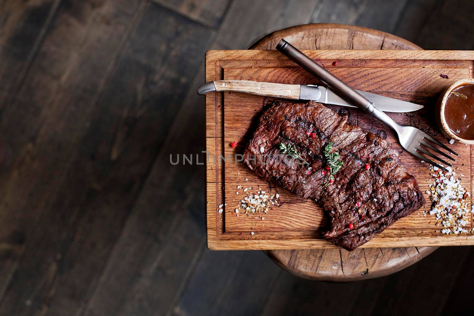 Beef steak. Piece of Grilled BBQ beef marinated in spices and herbs on a rustic wooden board over rough wooden desk with a copy space. Top view