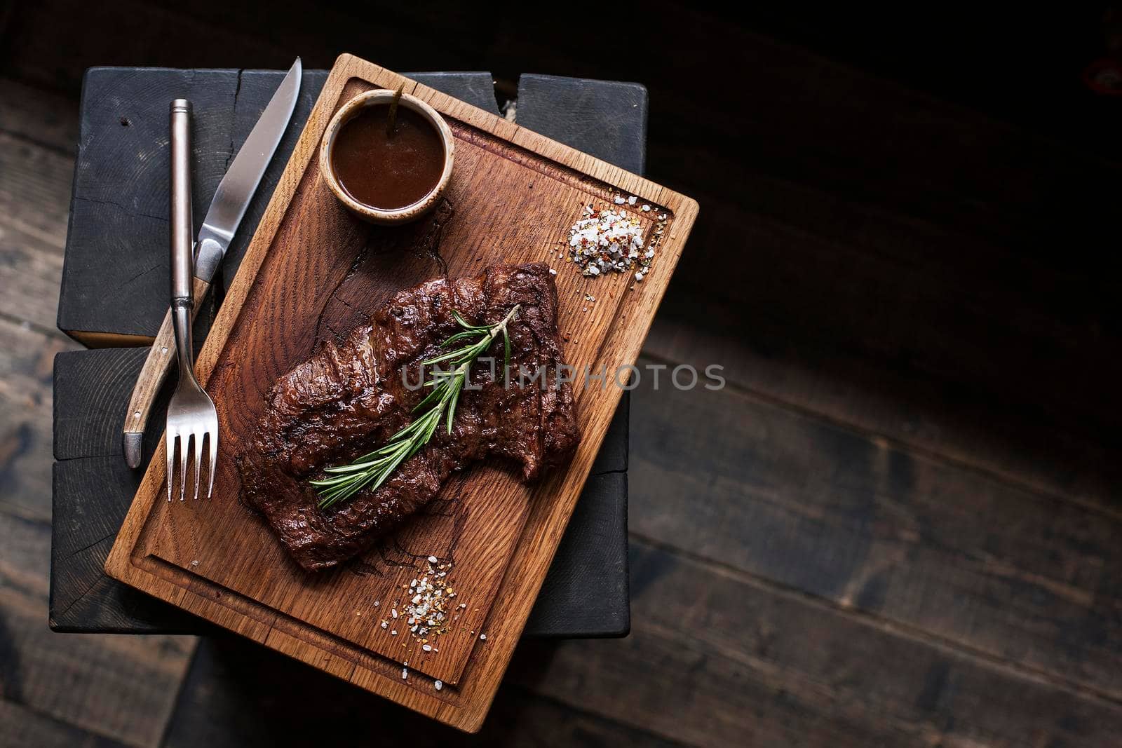 Beef steak. Piece of Grilled BBQ beef marinated in spices and herbs on a rustic wooden board over rough wooden desk with a copy space. Top view