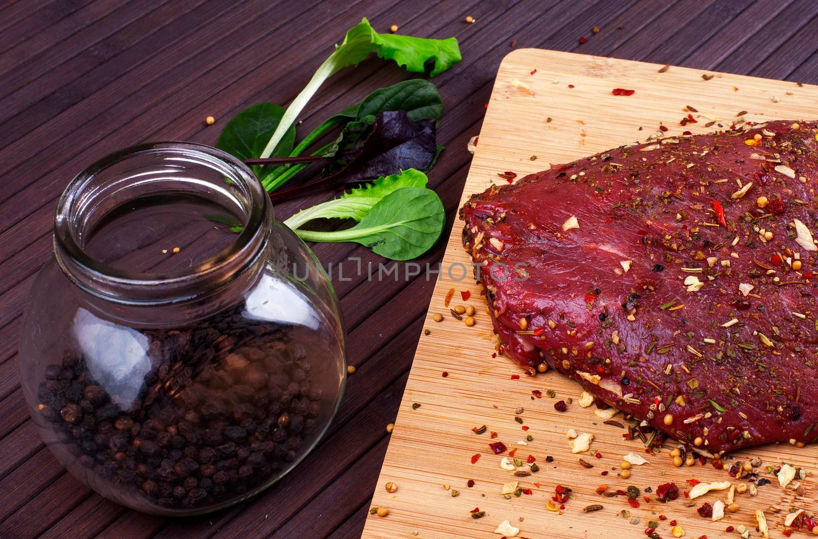 Raw Beef Roast with Fresh Herbs on a dark wooden table.