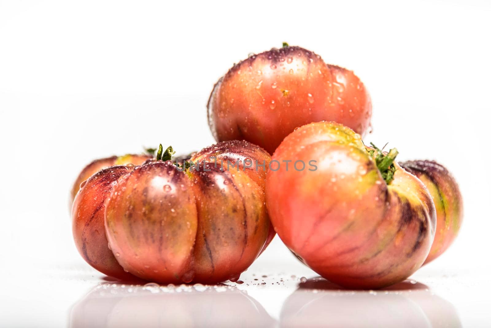 Several tomatoes of the tiger variety on a white background