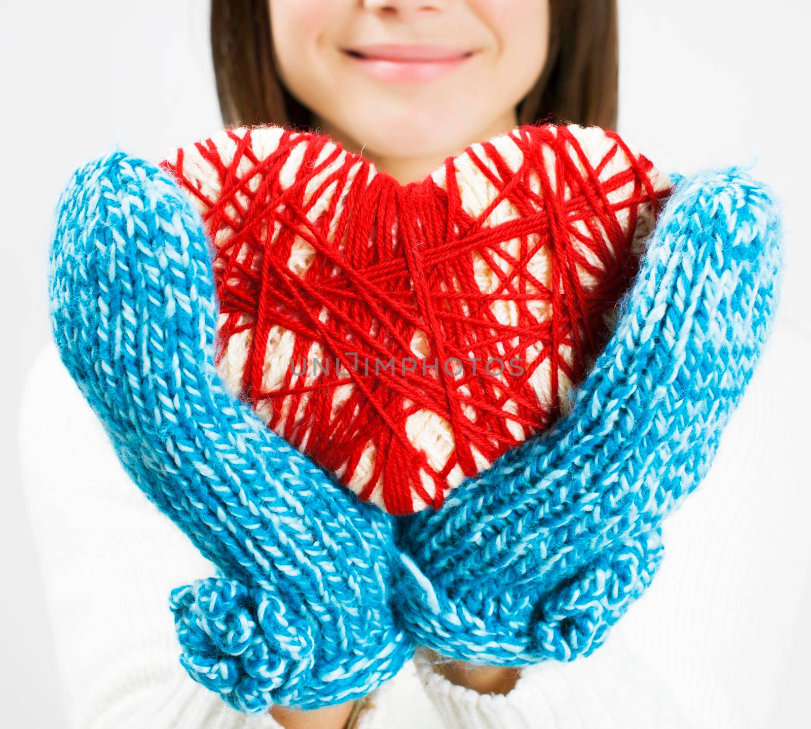 Girl hands in blue knitted mittens holding romantic red heart - by Jyliana