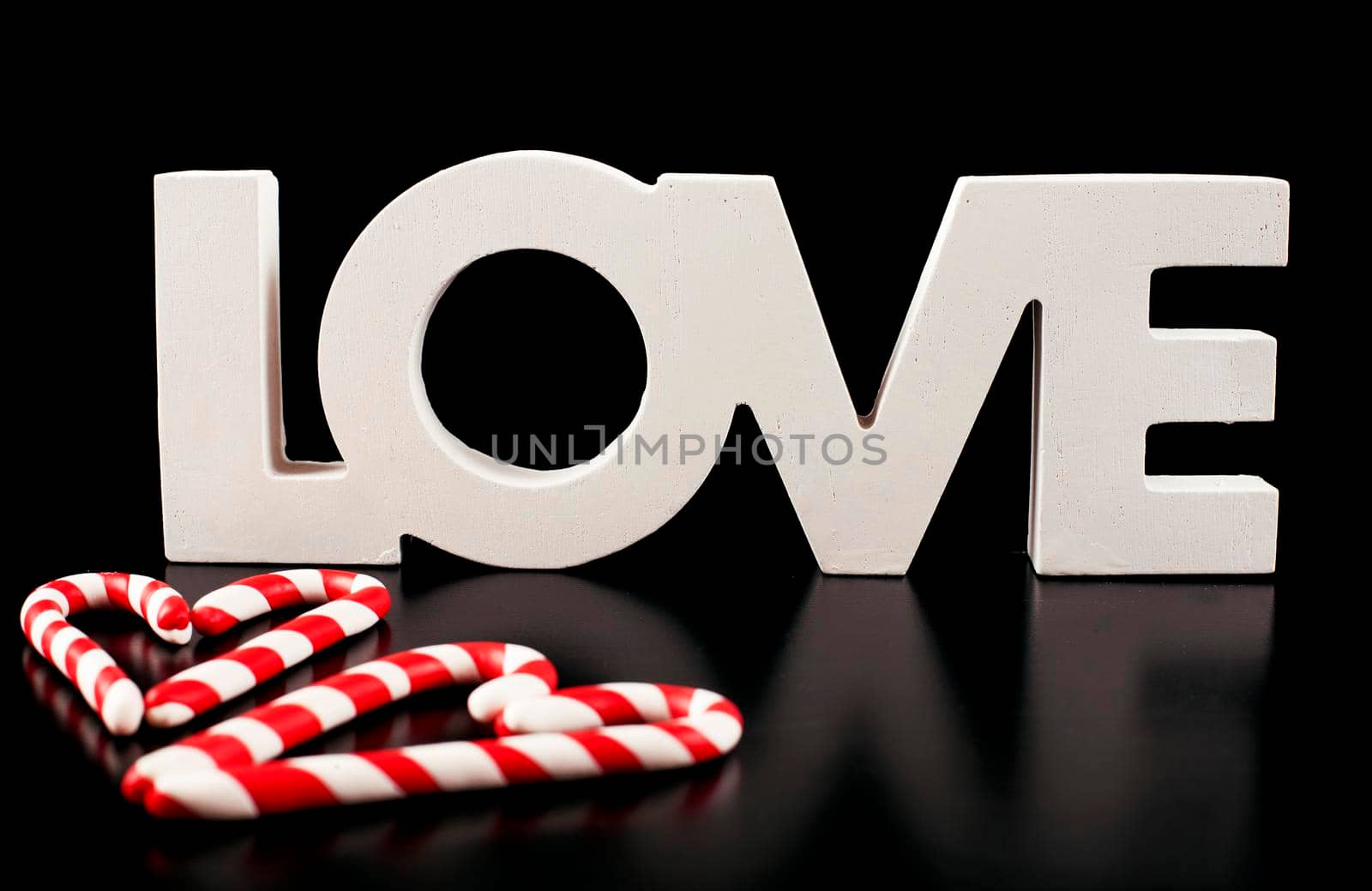 large letters LOVE and Valentine Heart made from Christmas candies isolated on black background