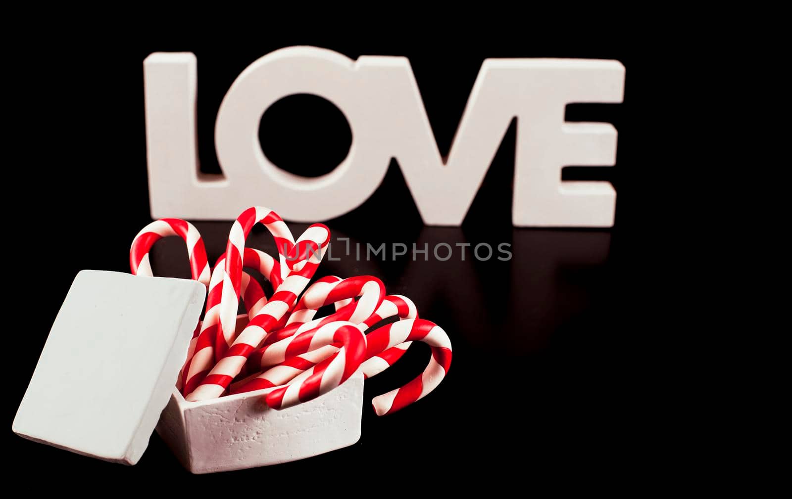 large letters LOVE and Valentine Heart made from Christmas candies isolated on black background