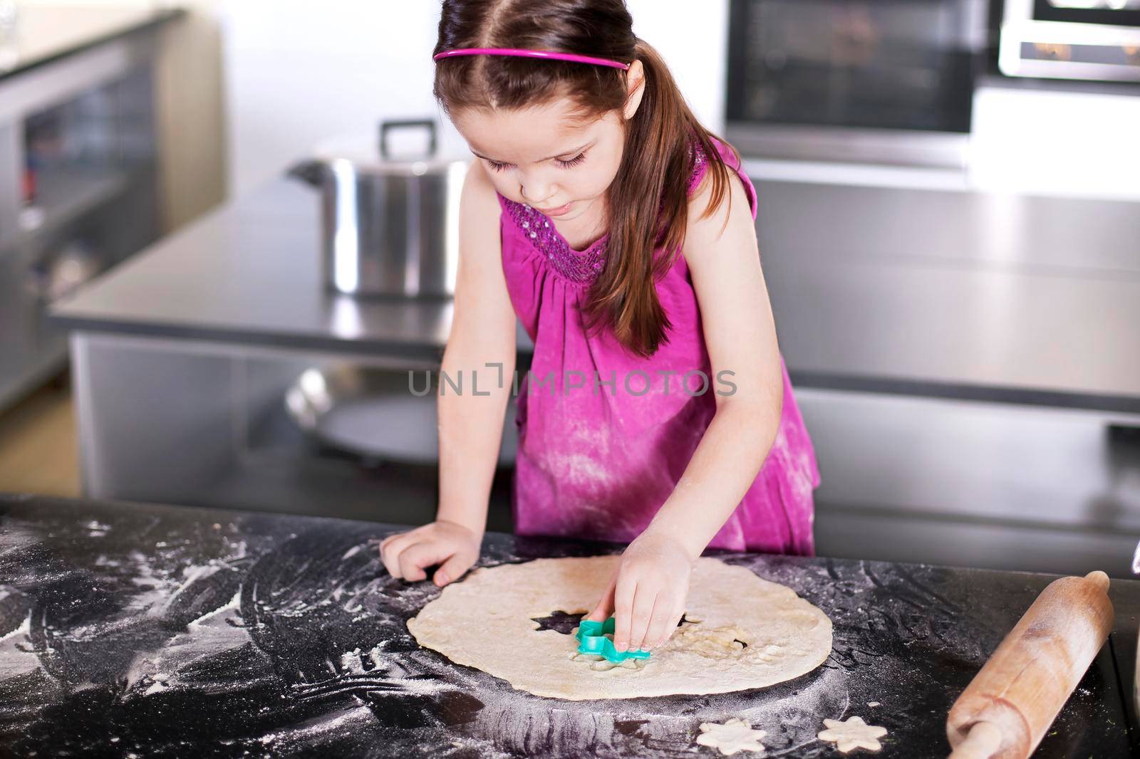 little daughter cooking in the kitchen at home. Girl Assisting In Preparing Food - Stock image