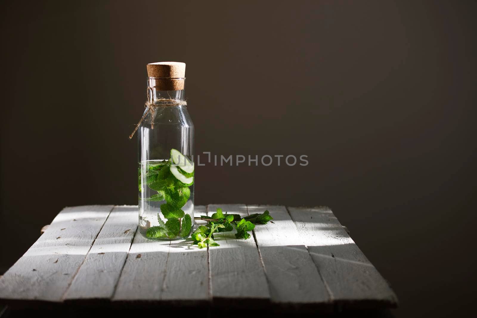 Nutritious detox water or lemonade with cucumber and mint on wooden table