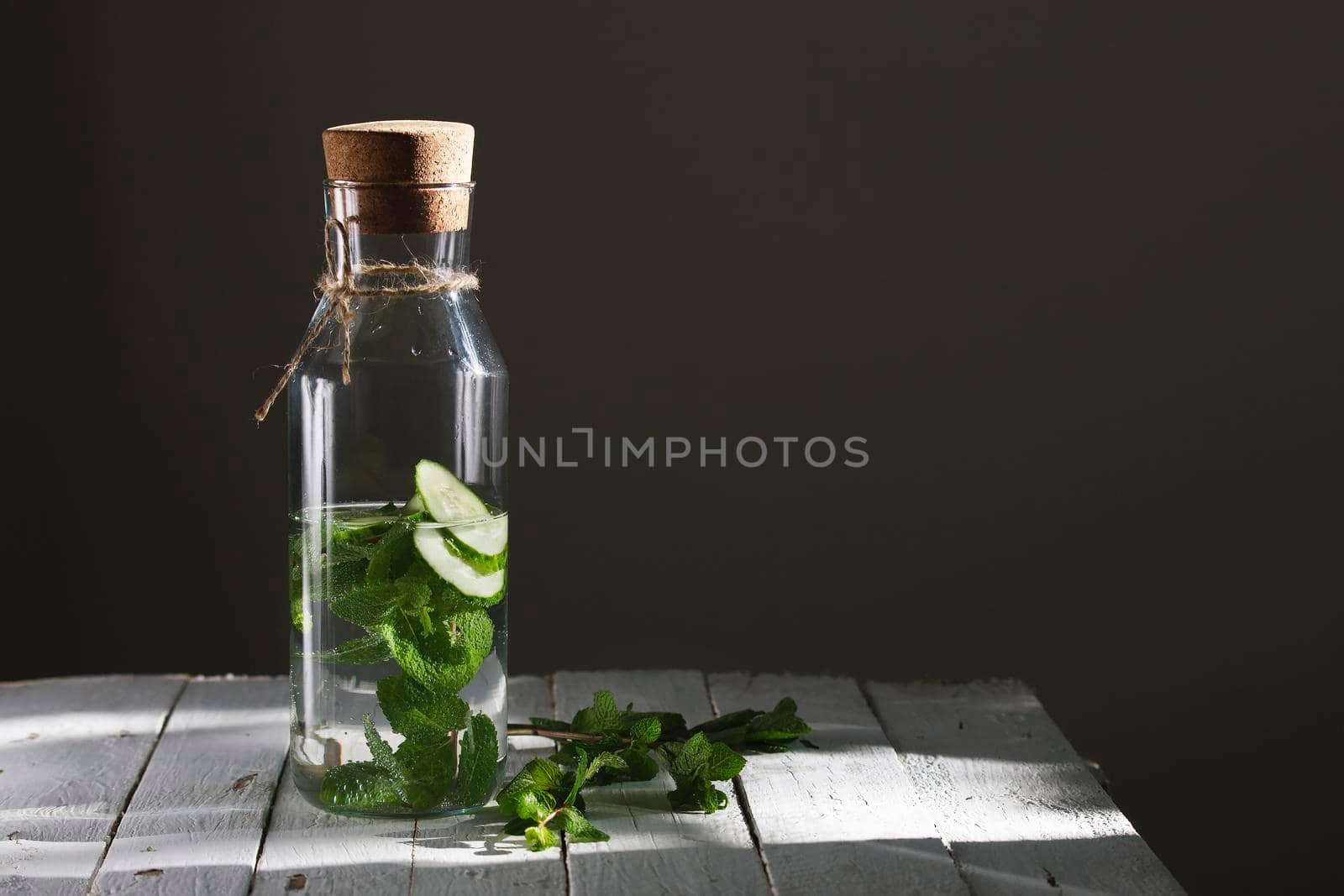 Nutritious detox water or emonade with cucumber and mint on wooden table