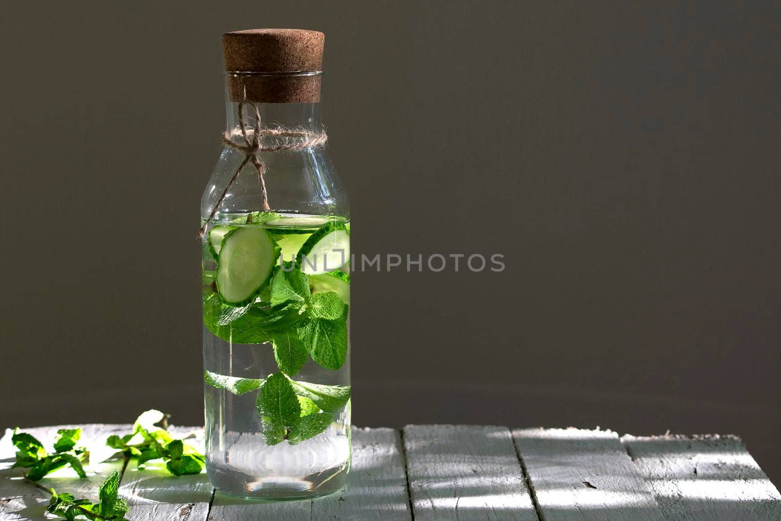 Nutritious detox water or emonade with cucumber and mint on wooden table. Copy space for text.