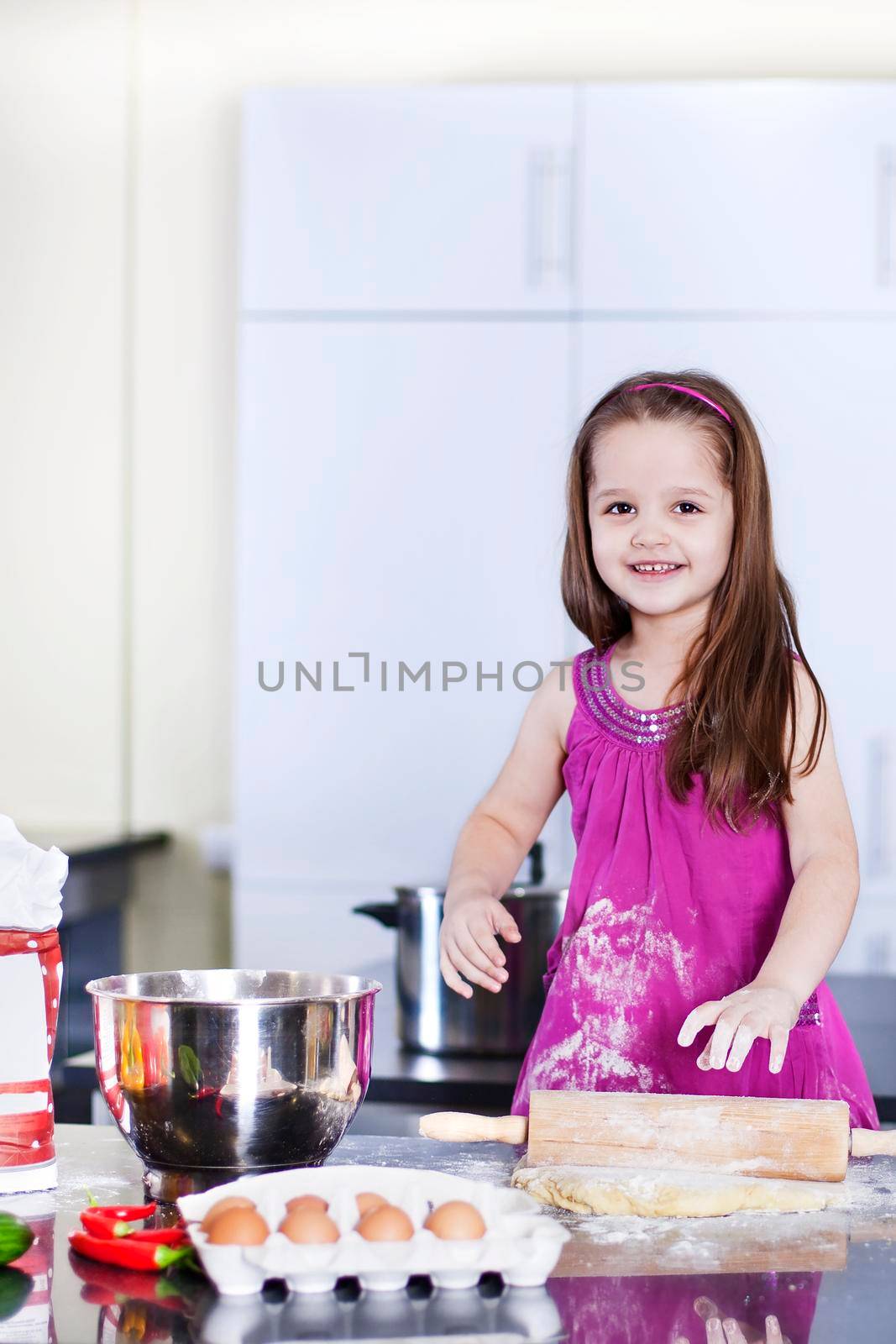 little daughter cooking in the kitchen at home. Girl Assisting In Preparing Food - Stock image