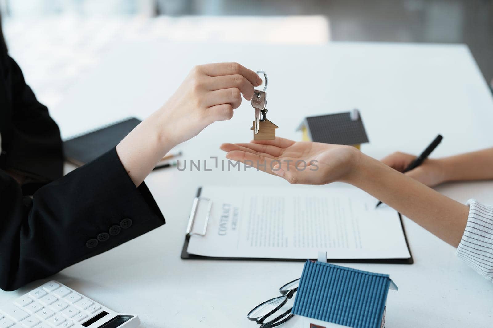 Accountant, businessman, real estate agent, Asian business woman handing keys to customers along with house after customers to sign.
