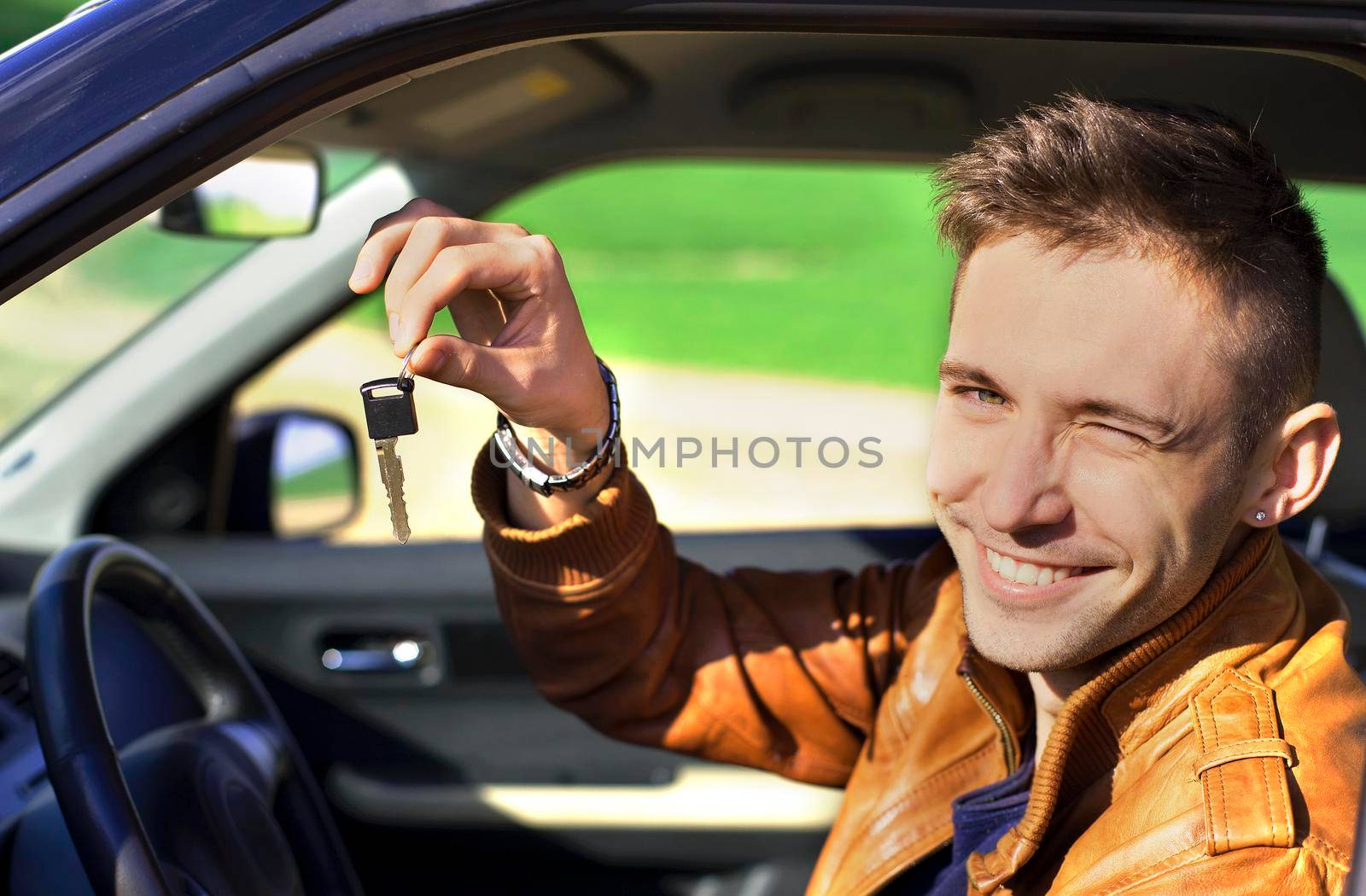 Man sitting inside car and showing keys to new car