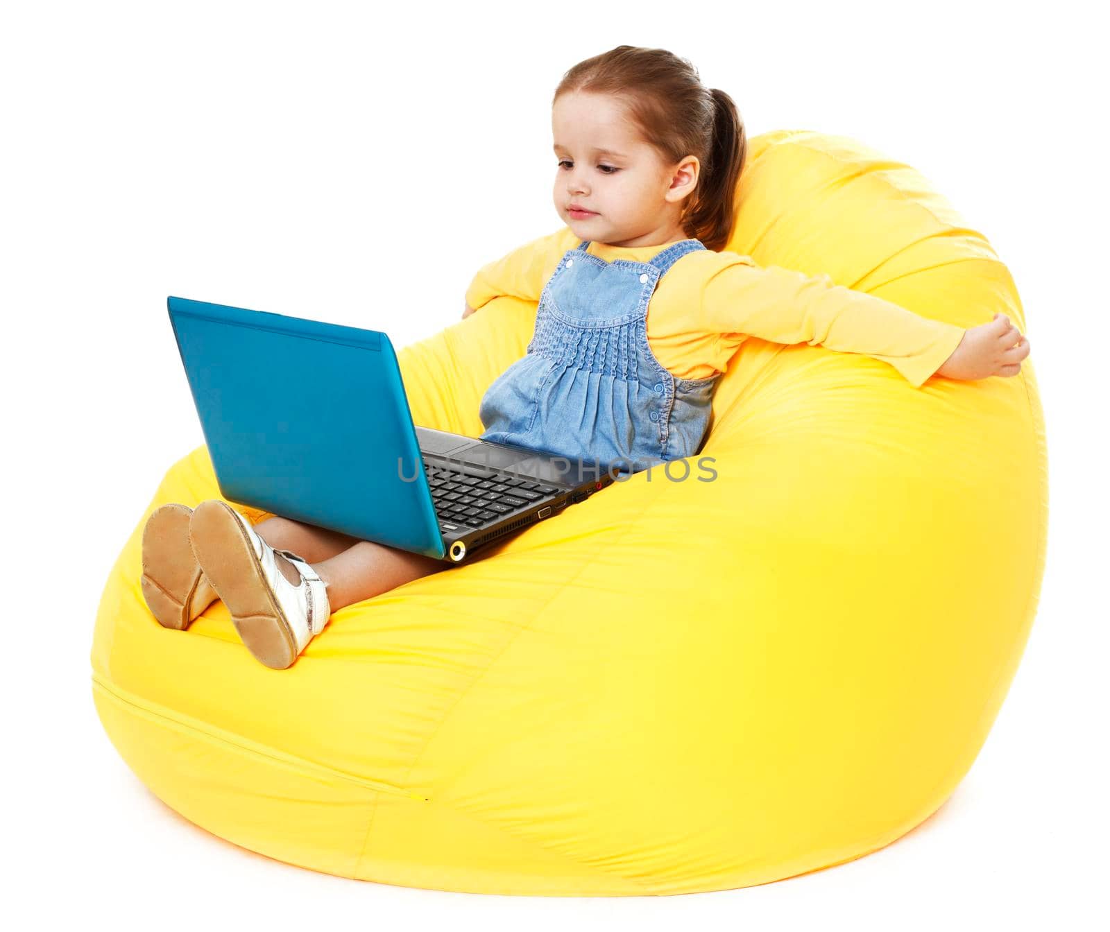 Child sitting on a bean bag with laptop - Stock Image by Jyliana