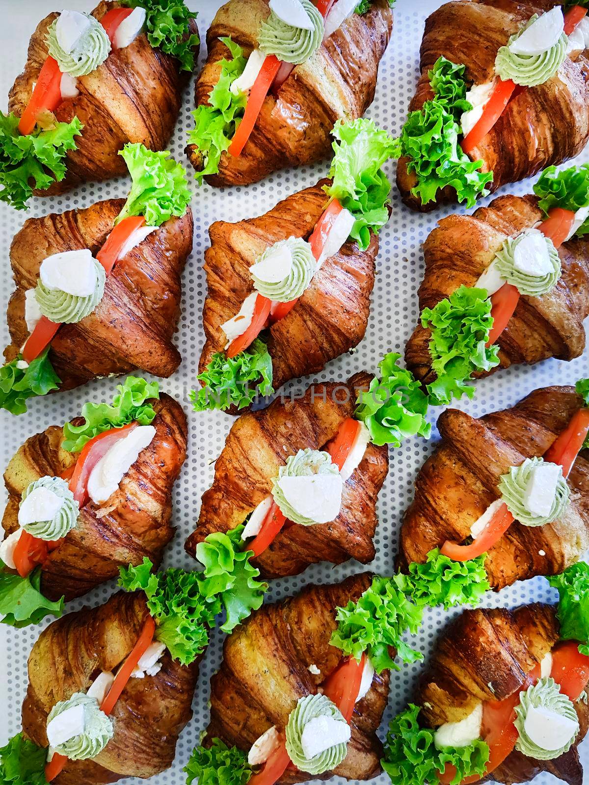 Breakfast sandwiches with mini croissants, smoked salmon slices and parsley on patterned background. Croissants with red fish and herbs. Breakfast meal