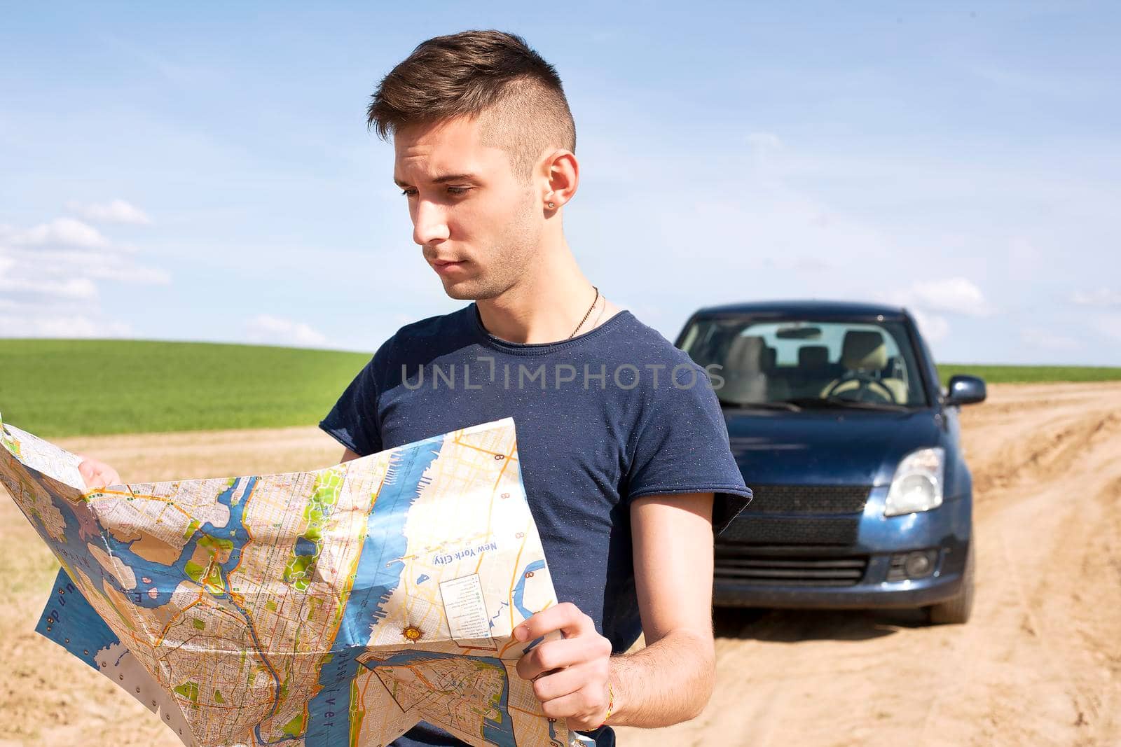 Photo of a traveler parked his car by the side of a road, lost and reading the NYC map. Focus on the map and male.