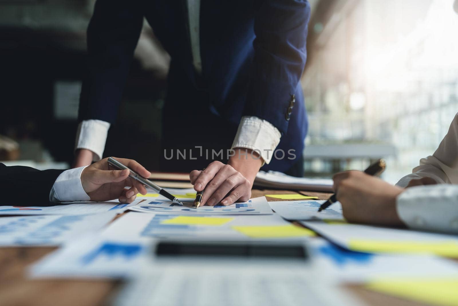 Male businessman pointing to take summarizing marketing strategy documents with female colleagues in meeting, teamwork, investment planning.