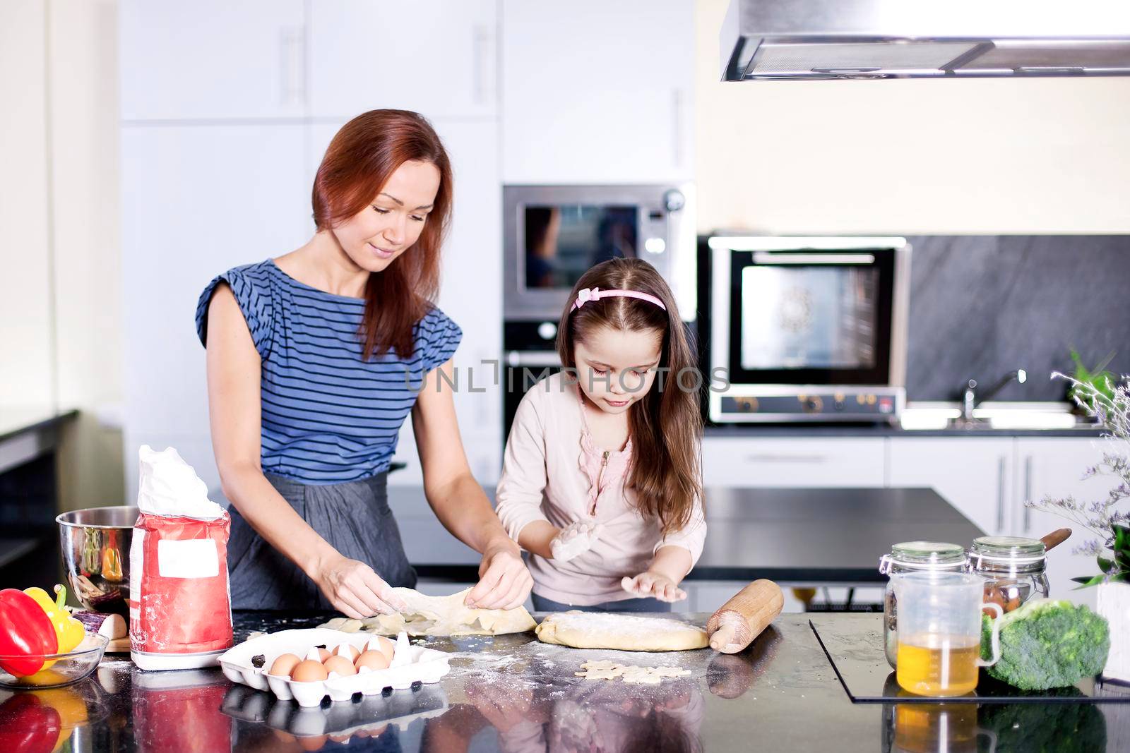 Mother with little daughter cooking by Jyliana
