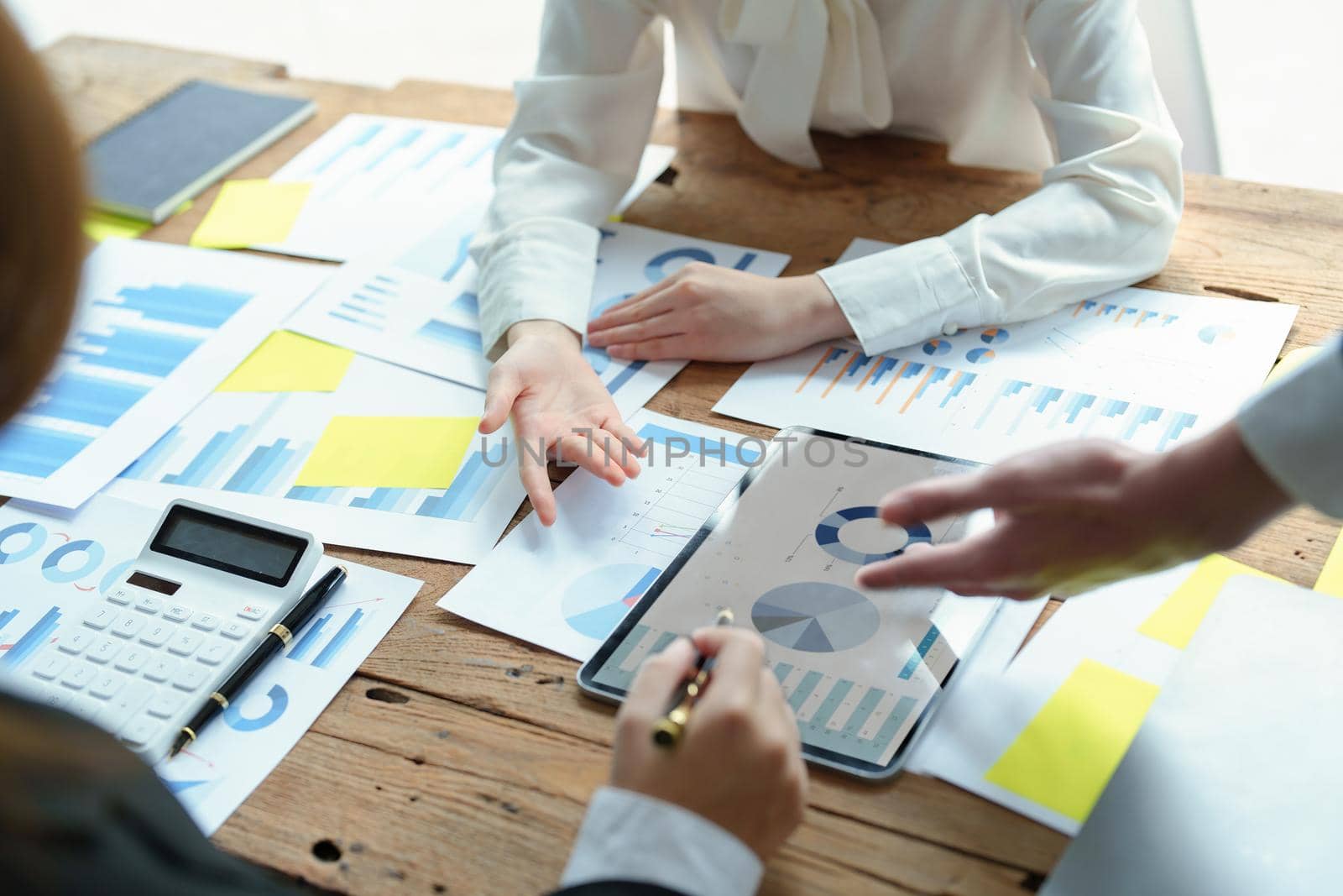 Male businesswoman pointing to tablet monitor summarizing marketing strategy with female colleagues in meeting, teamwork, investment planning.