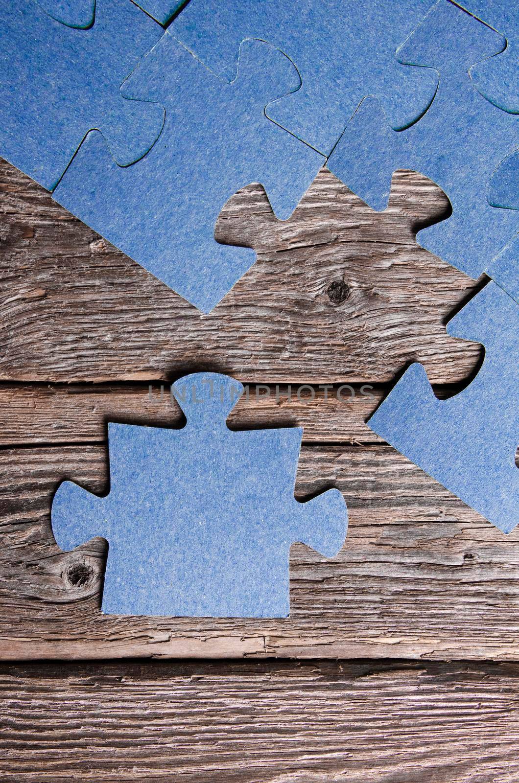 Incomplete puzzles lying on wooden rustic boards. Conceptual of innovation, solution finding and integration. Hand with puzzle piece