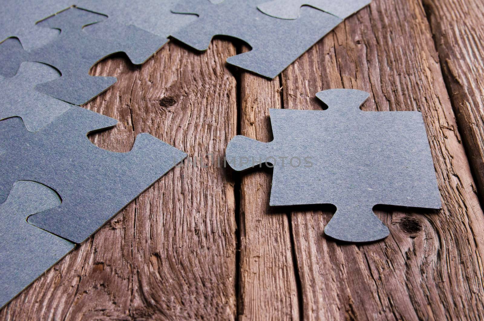 Incomplete puzzles lying on wooden rustic boards. Conceptual of innovation, solution finding and integration. Hand with puzzle piece